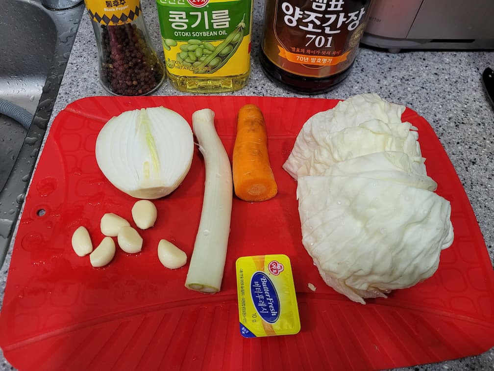 빨간 도마 위 양배추 양파 마늘 대파 버터 양념병