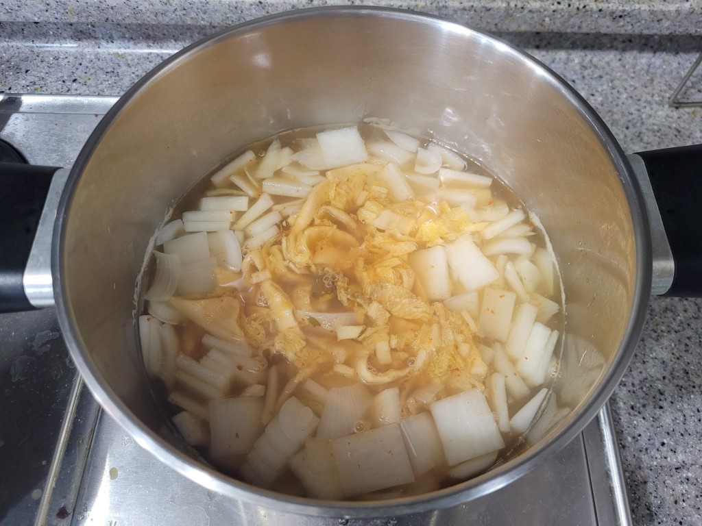 육수 속에서 끓고 있는 묵은지와 무 양파