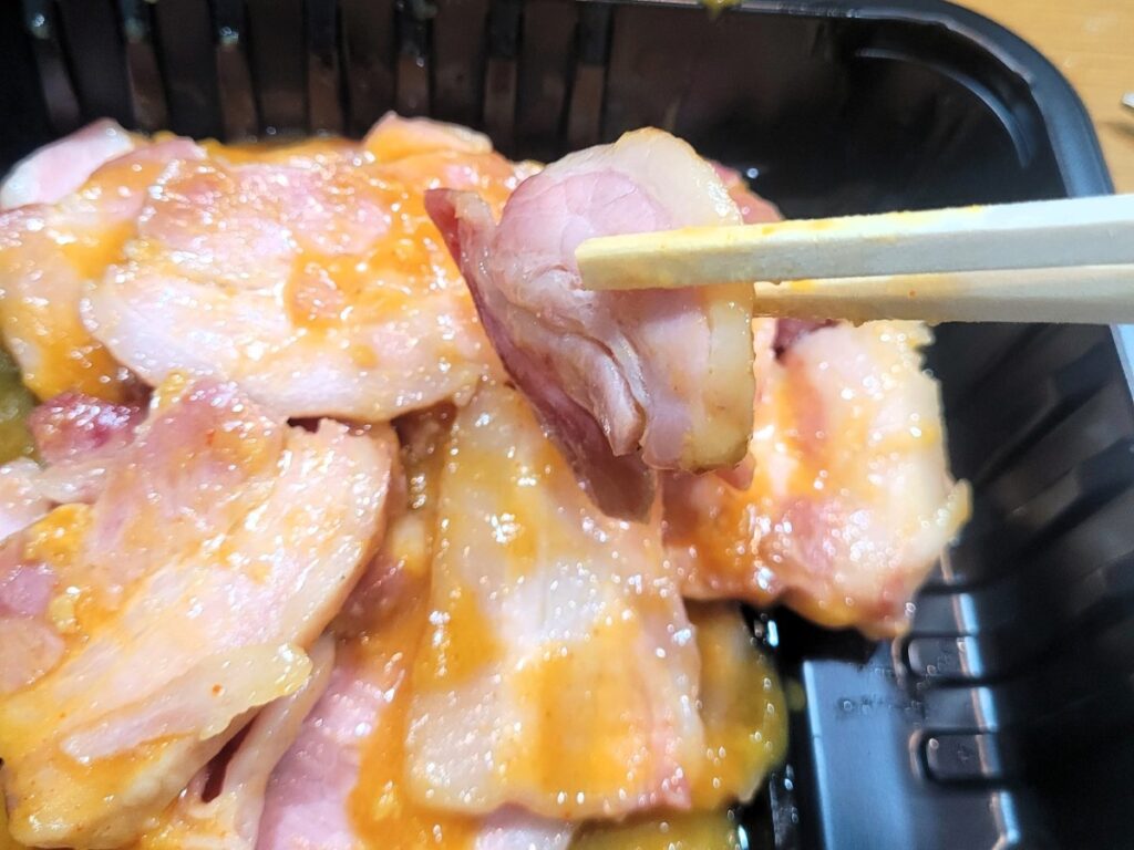젓가락으로 집은 마늘겨자소스 훈제삼겹살 한 점