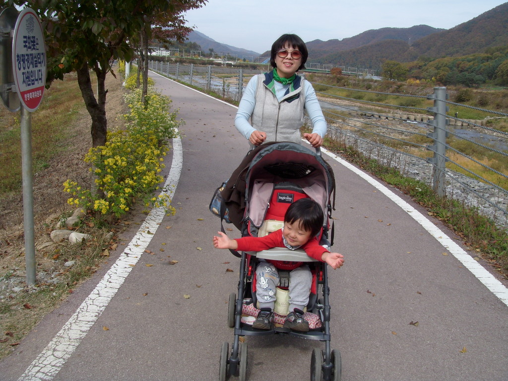 미소 성인, 유모차 행복한 아이, 강변 산책로 가을 산.