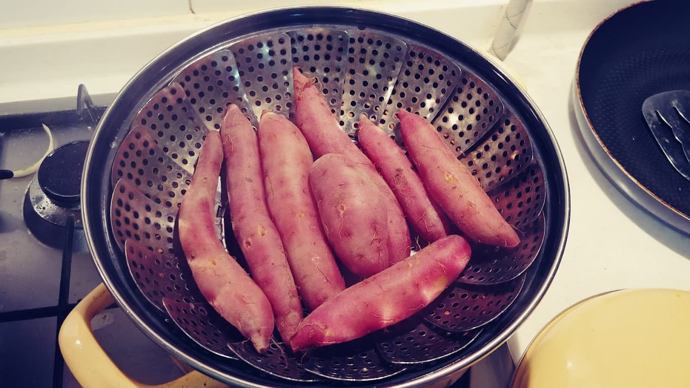 가스레인지 위 찜기 안 붉은색 고구마 여러 개.