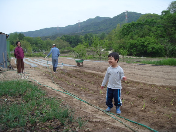 미소 짓는 아이, 농부가 밭에 물 주는 농촌 풍경