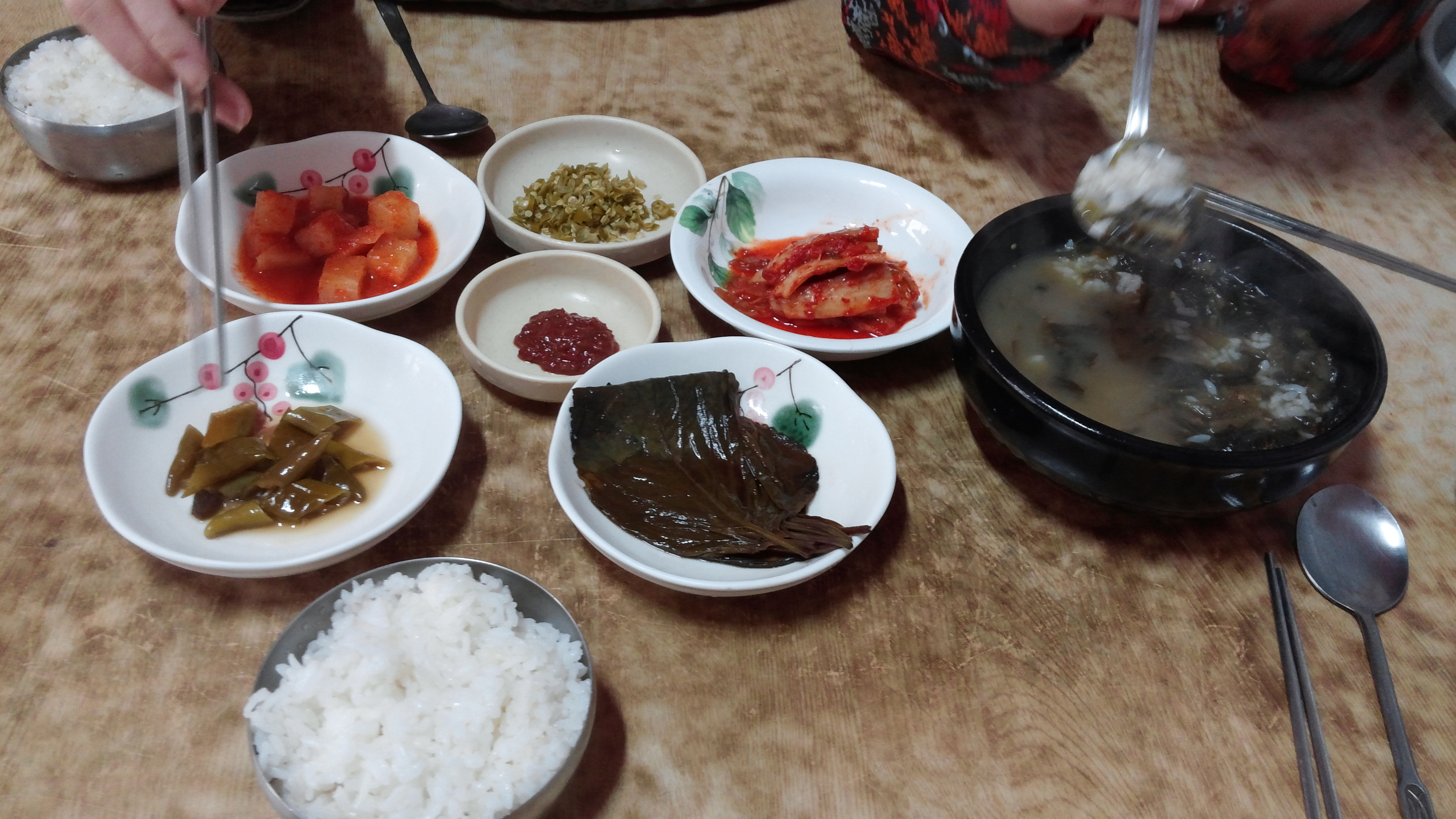 식탁 위 푸짐한 한식 반찬, 뜨거운 찌개, 쌀밥.