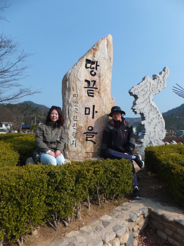 두 방문객 땅끝마을 바위 기념비와 한반도 조형물 옆에 앉음