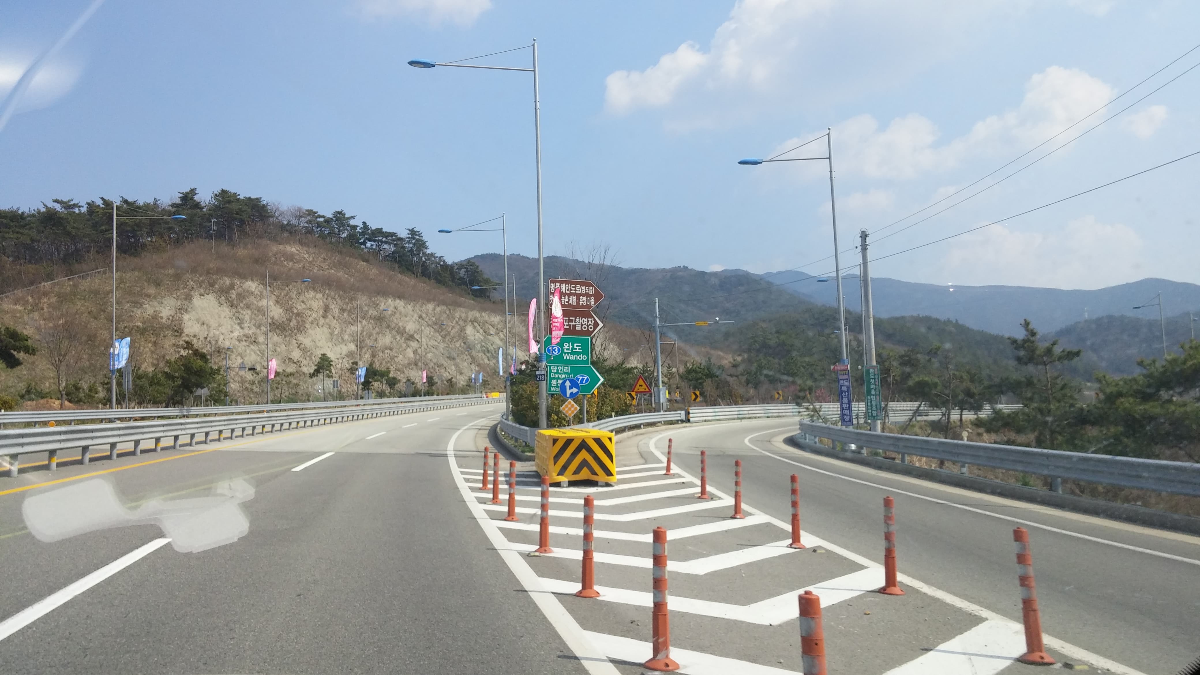 산악 도로, 완도 방향 표지판, 노란색 분리대, 주황색 볼라드.
