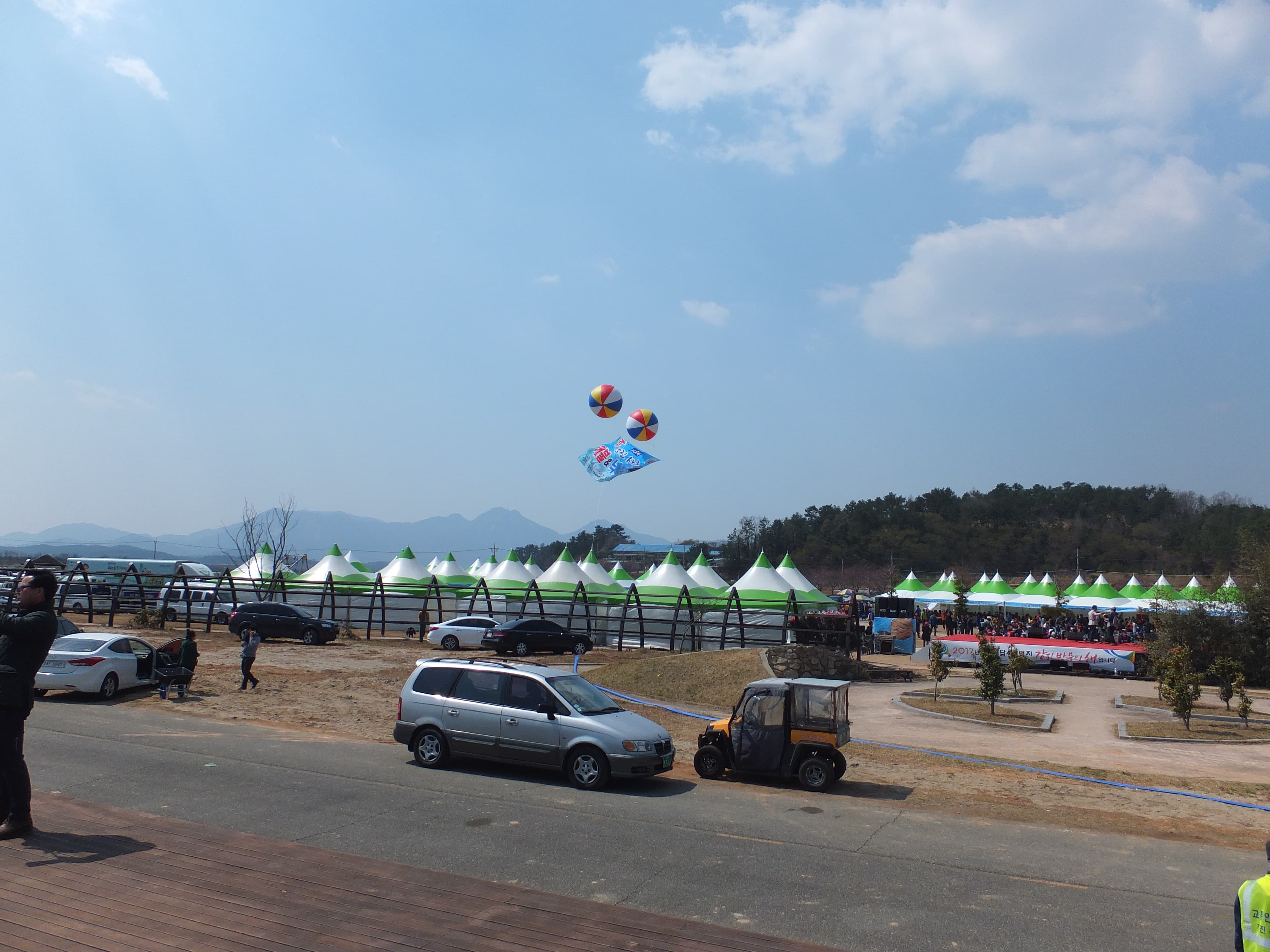 푸른 하늘 아래 야외 축제, 녹색 텐트, 풍선 연, 무대