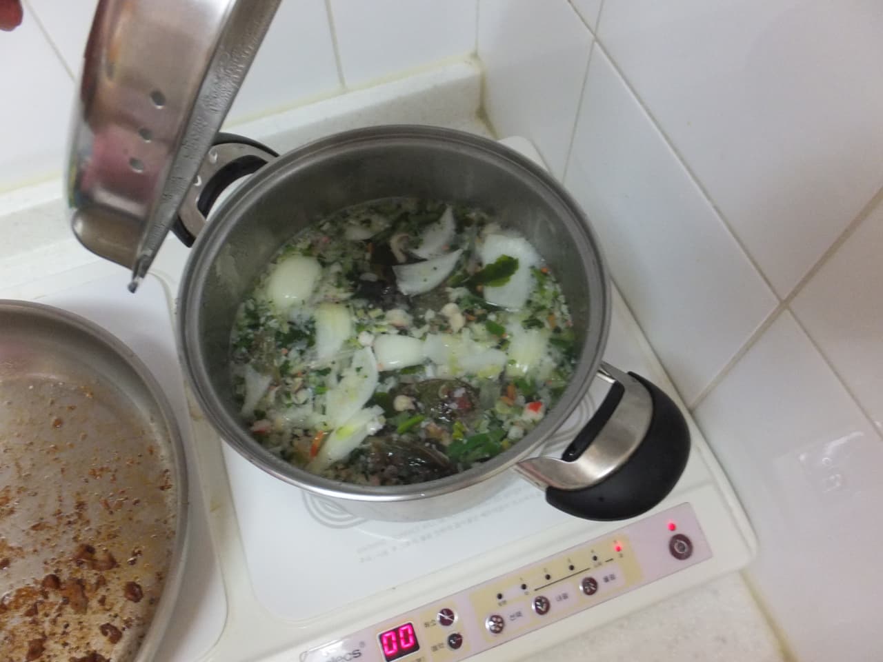 끓는 해산물, 양파, 채소 가득 찌개, 인덕션 위 조리