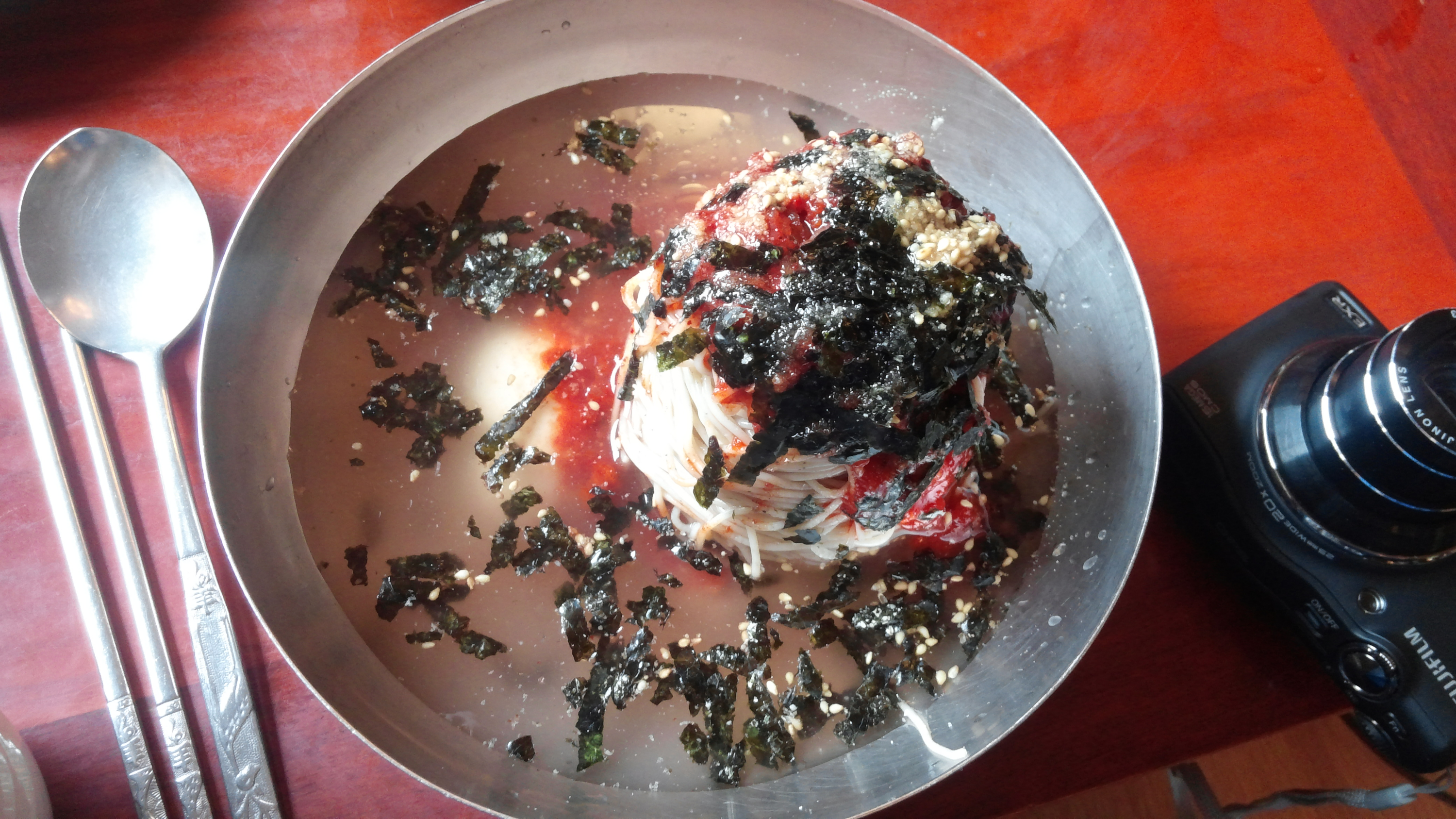 스텐 그릇에 담긴 시원한 막국수, 빨간 양념 김가루 참깨 고명