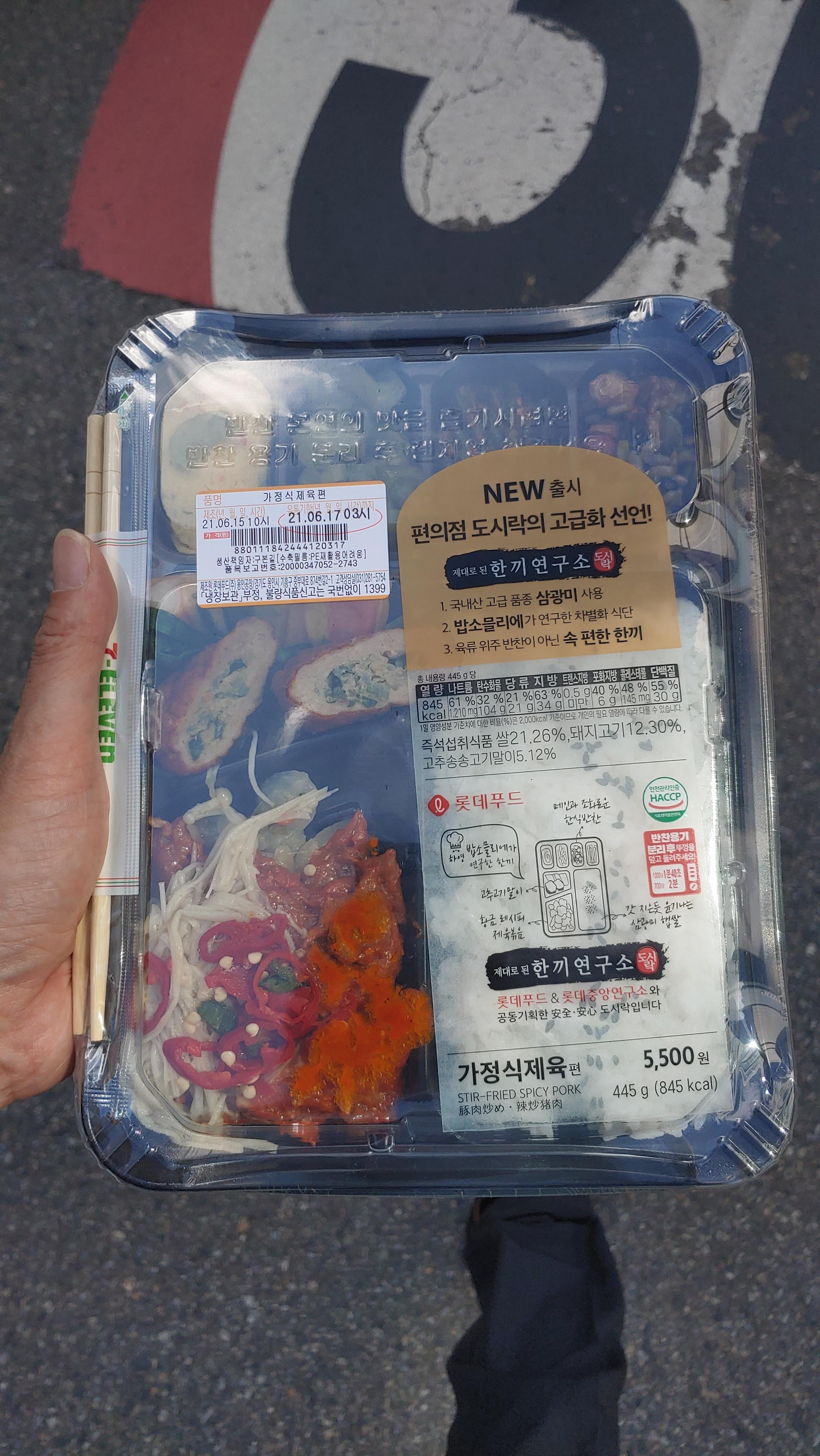 손에 든 편의점 제육볶음 도시락, 밥, 만두, 다양한 반찬