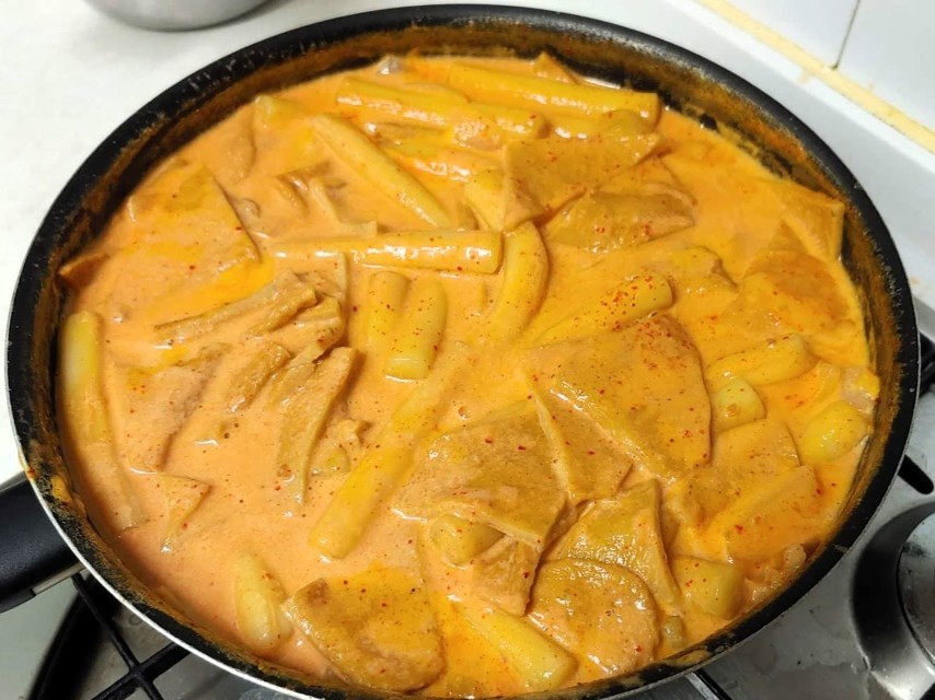 끓는 검은 냄비 속 매콤 주황 크림 로제 떡볶이, 어묵