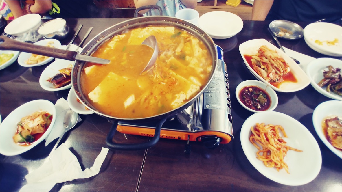 끓는 찌개, 다양한 한식 반찬, 휴대용 가스레인지 식탁