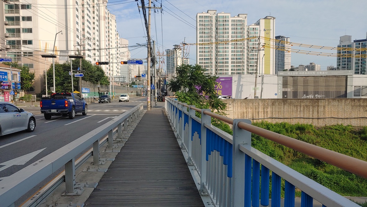 주거지역 도로, 아파트 단지, 보행교, 차량, 푸른 난간, 맑은 하늘
