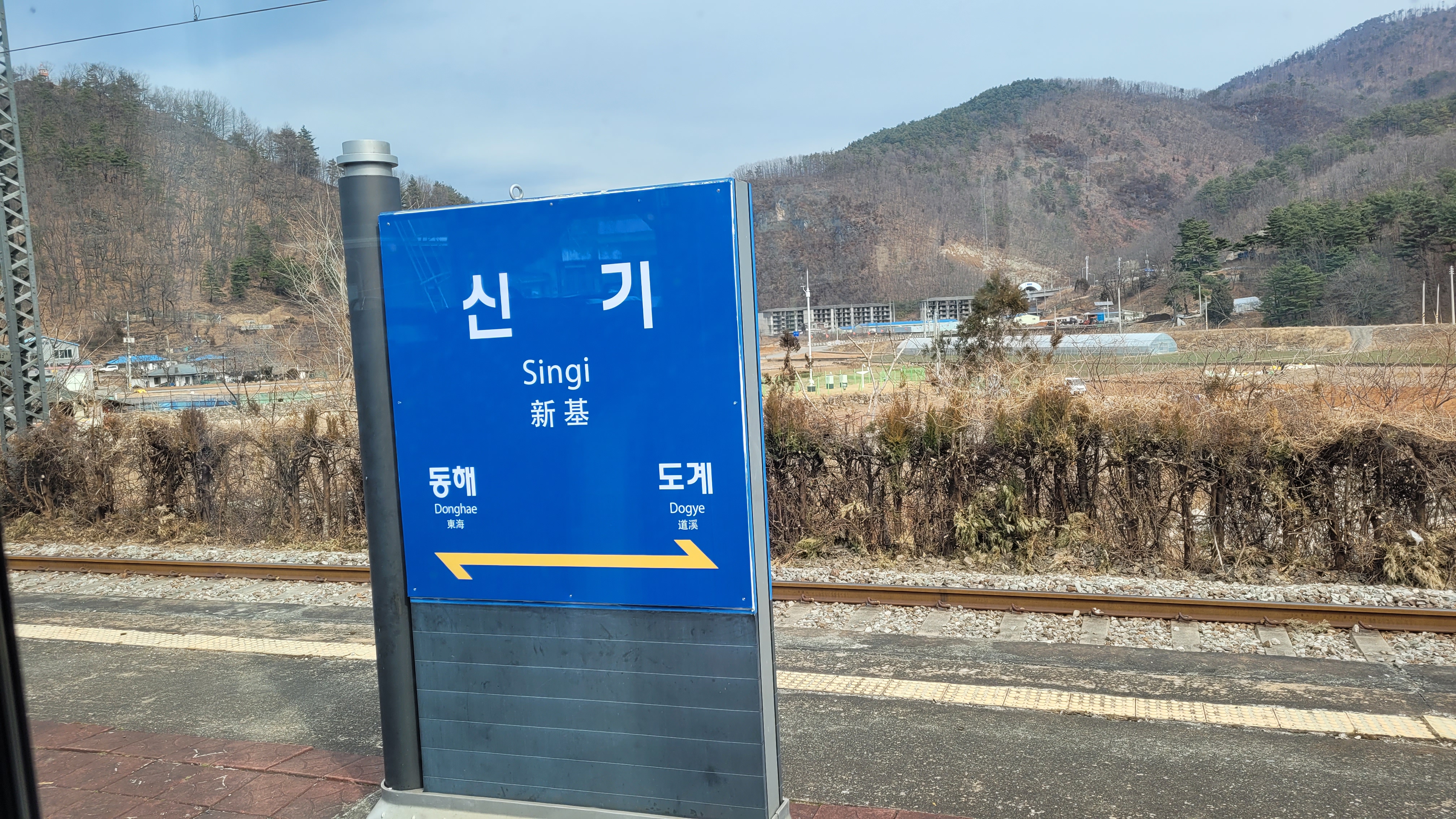 신기역 파란색 역명판, 산과 철길 풍경