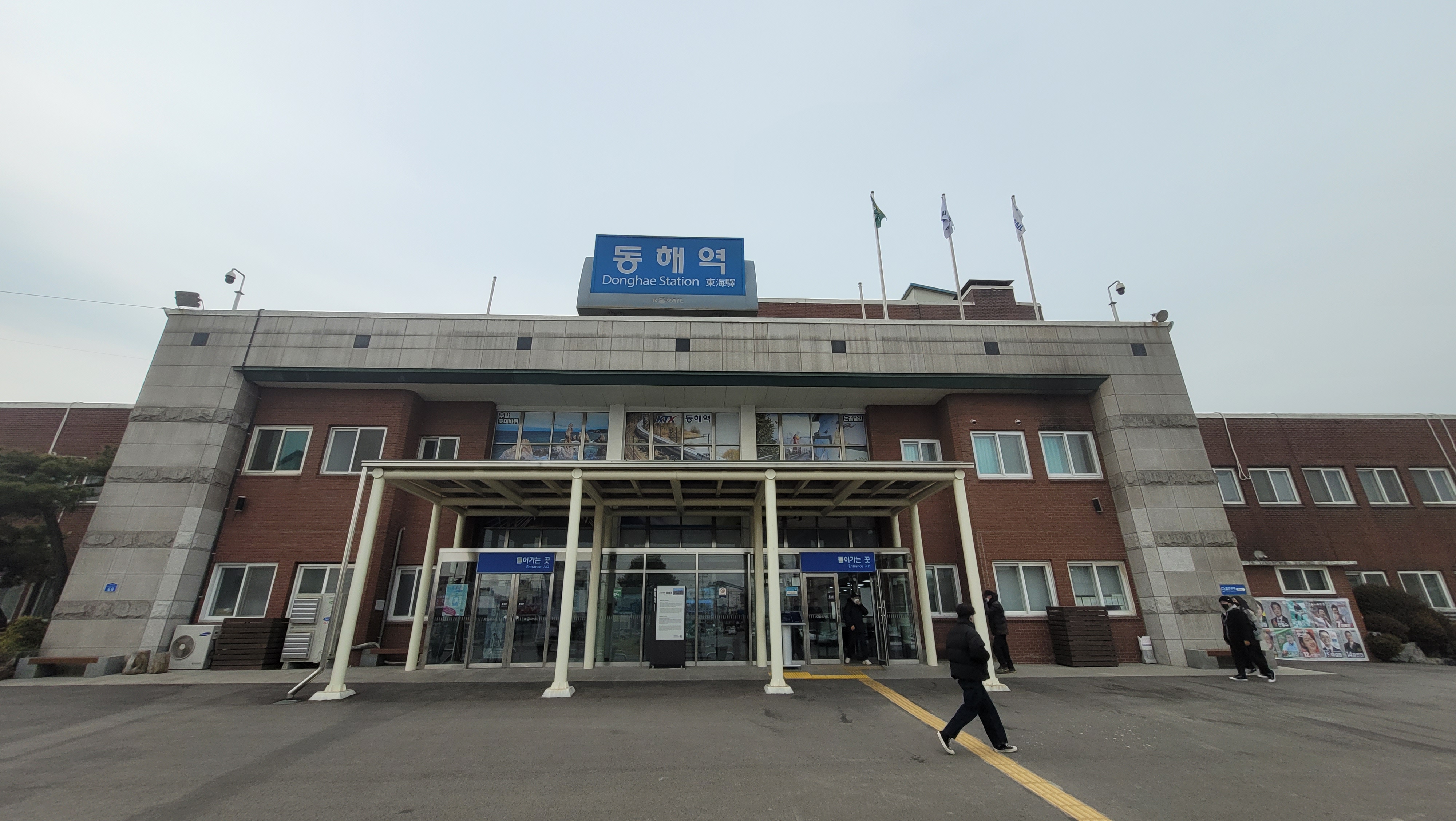 동해역 붉은 벽돌 석재 건물, 출입구 캐노피, 파란색 역명 간판.