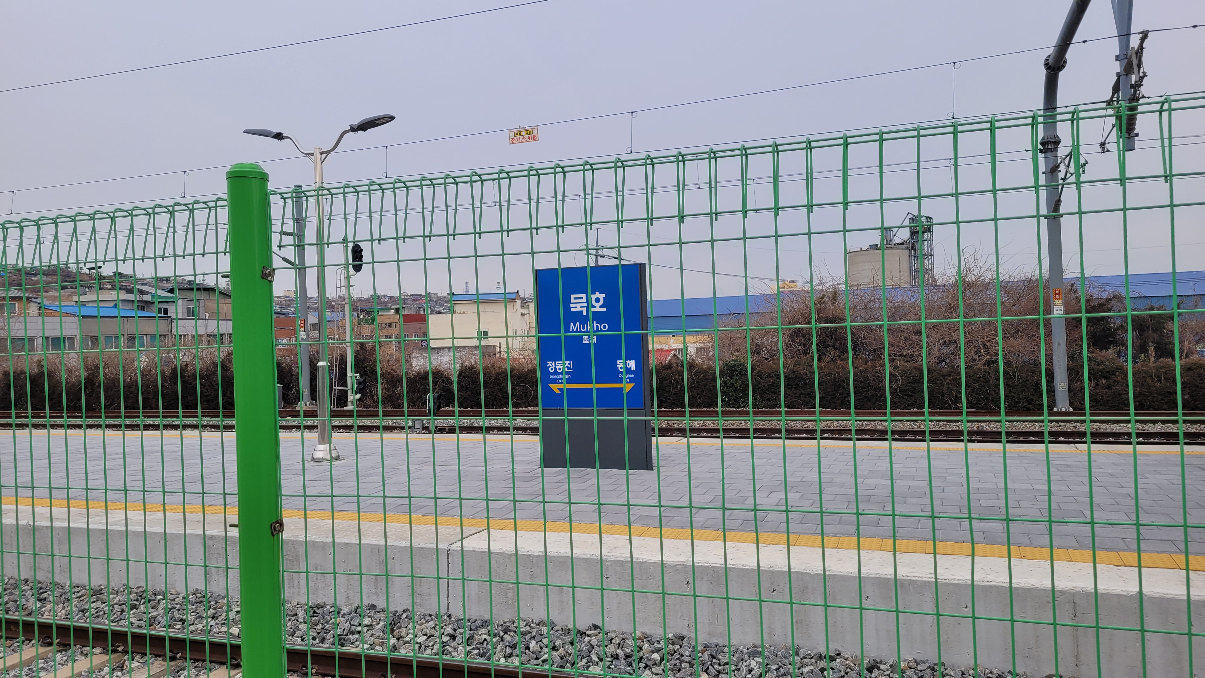 녹색 울타리 뒤 묵호역 플랫폼, 기찻길, 파란 역명판