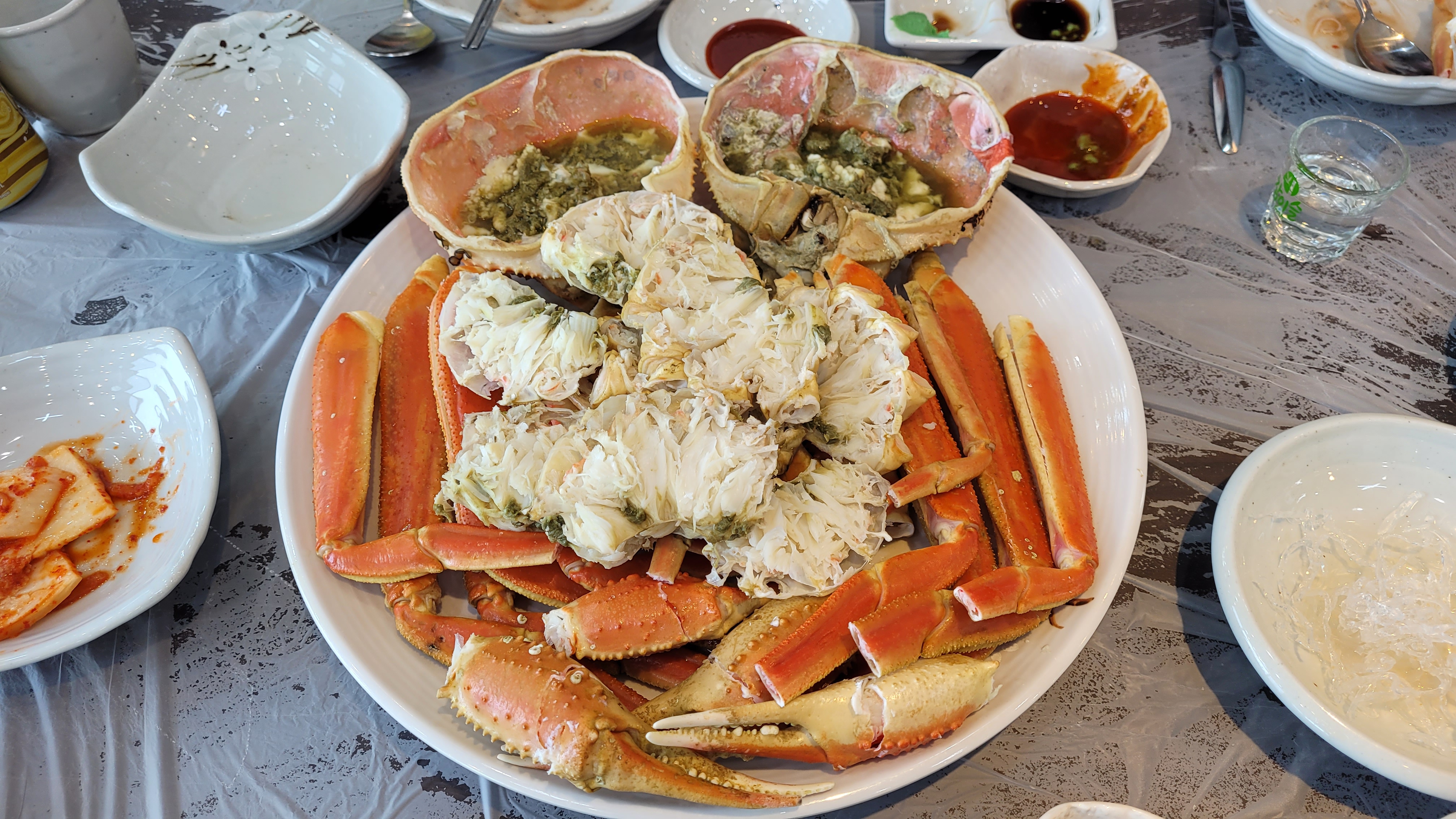 큰 접시에 푸짐하게 놓인 찐 대게, 게살, 게장, 밑반찬.