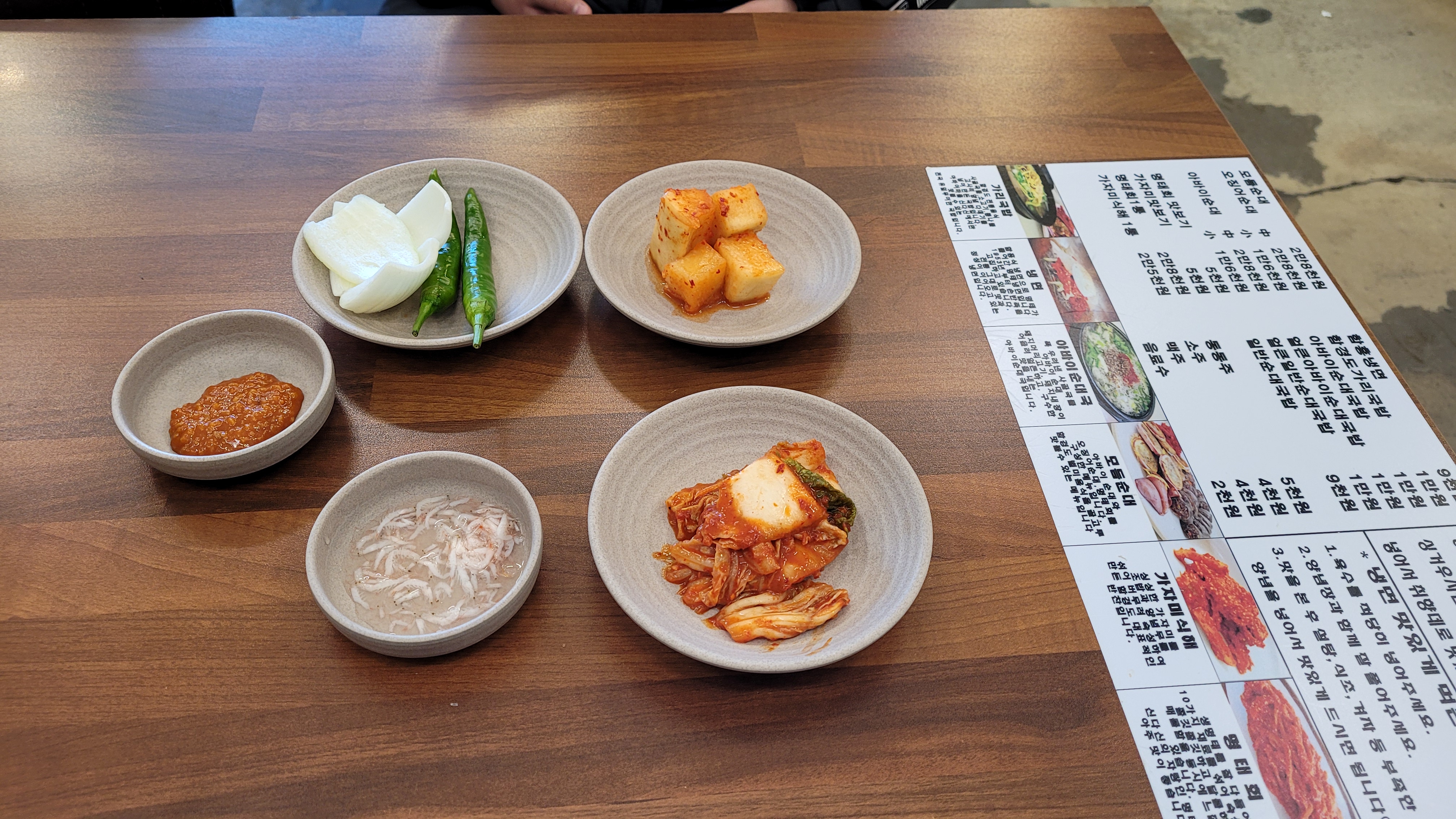 나무 테이블 위 한국 반찬, 김치, 깍두기, 고추, 쌈장, 새우젓