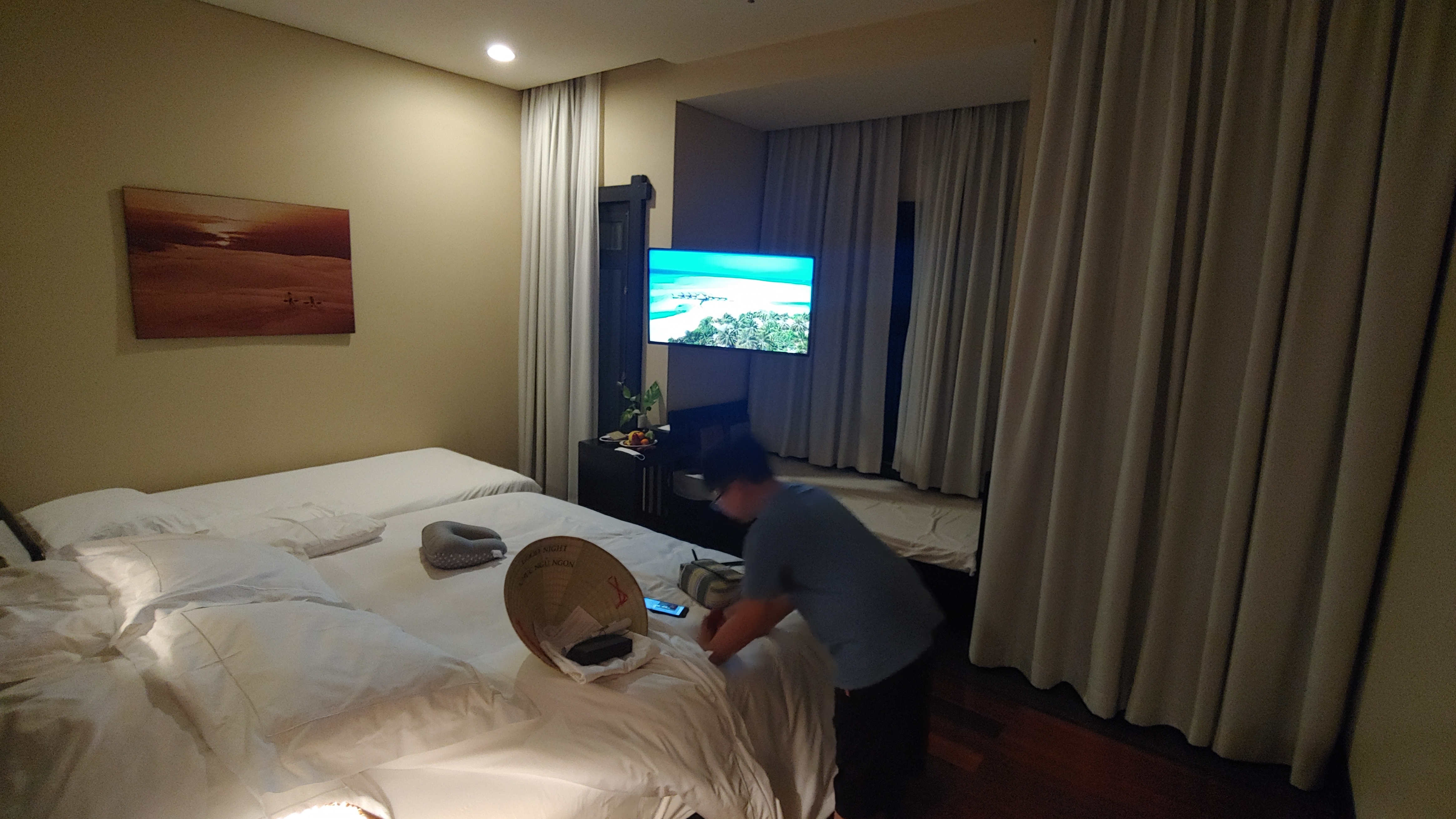 따뜻한 호텔 침실. 흰 침대 두 개, 벽걸이 TV, 베트남 모자.