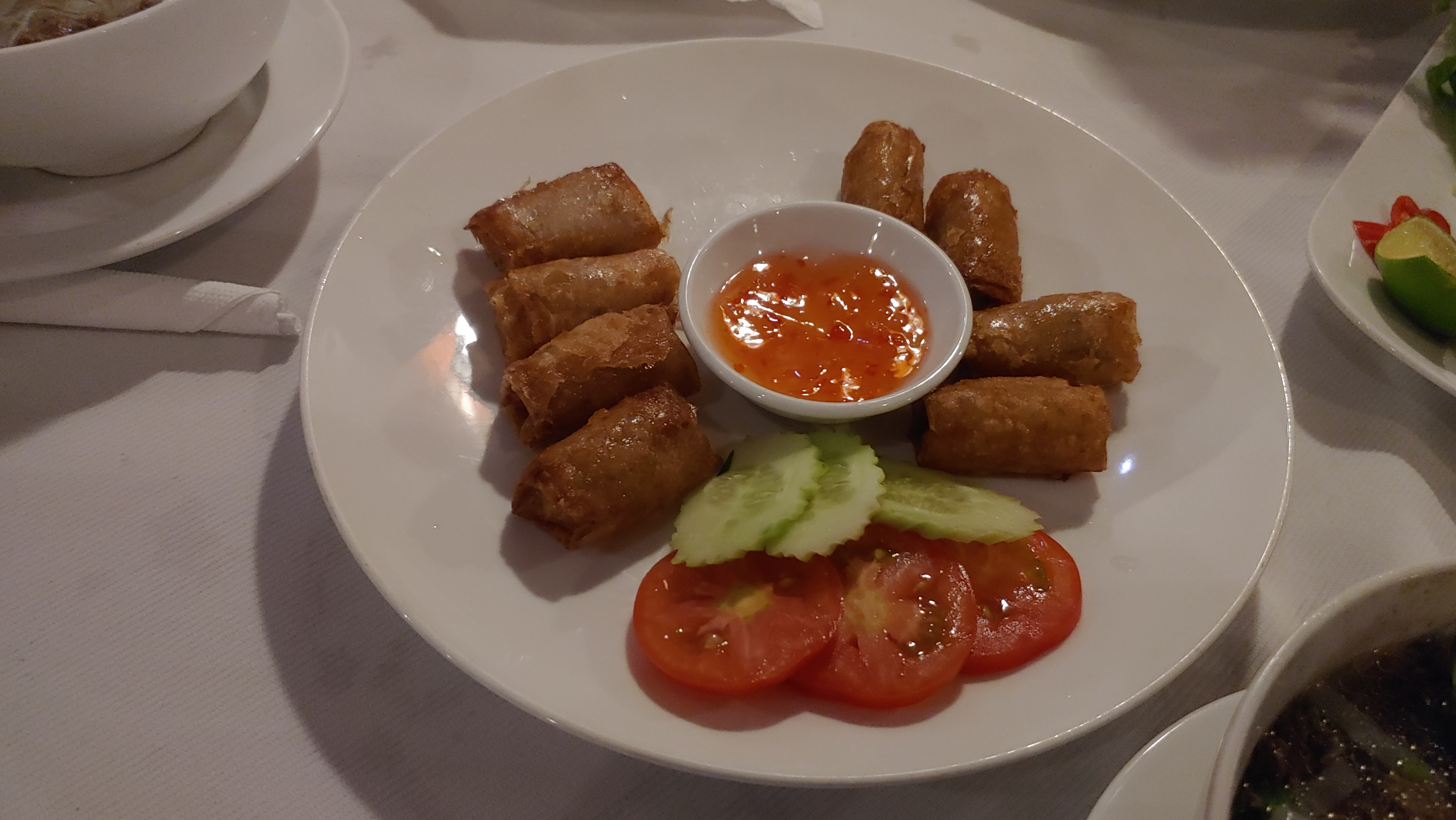 흰 접시 바삭한 짜조, 오이, 토마토, 달콤한 칠리 소스