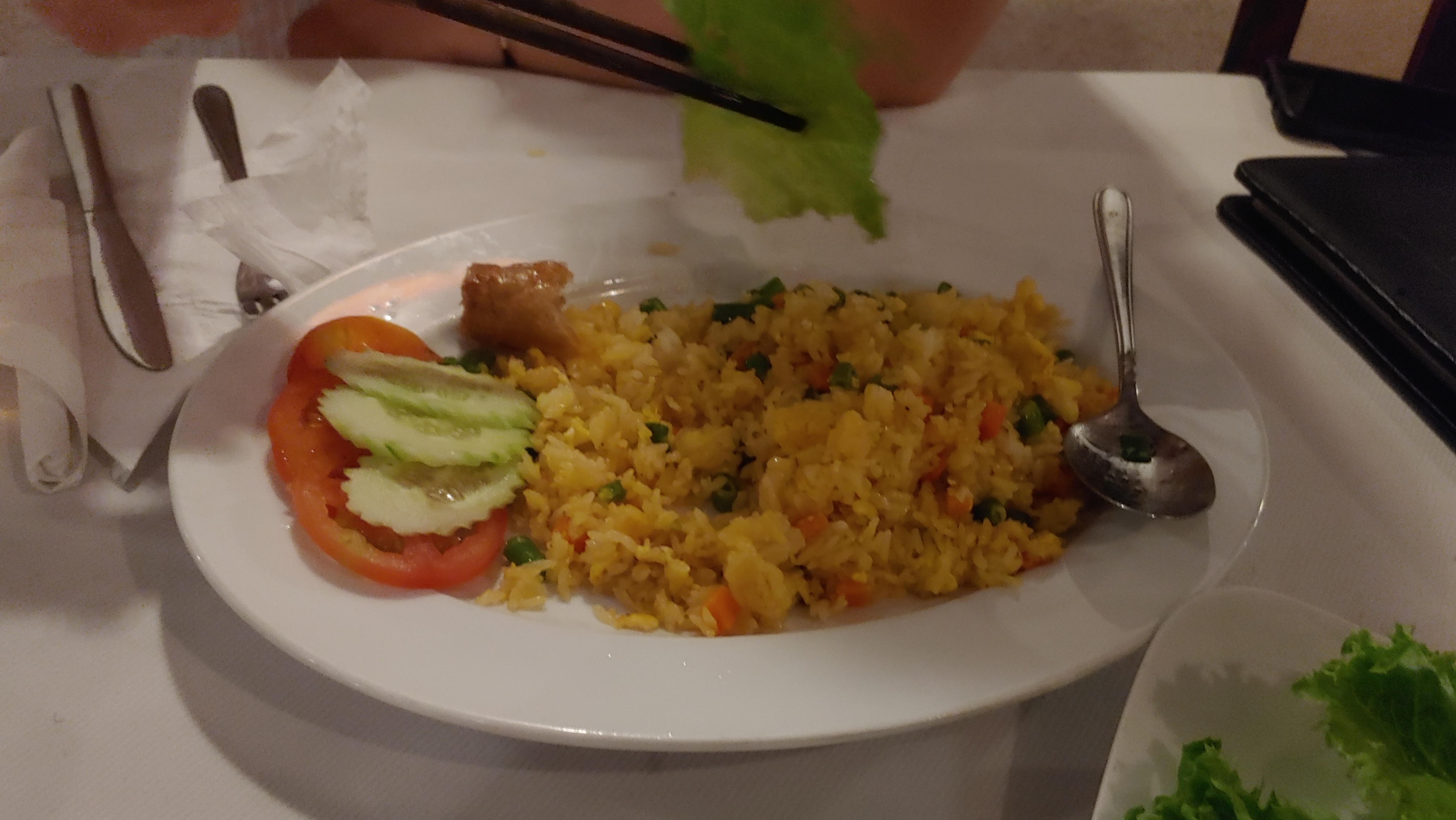 흰 접시 위 야채 볶음밥, 토마토, 오이. 젓가락 상추 잎.
