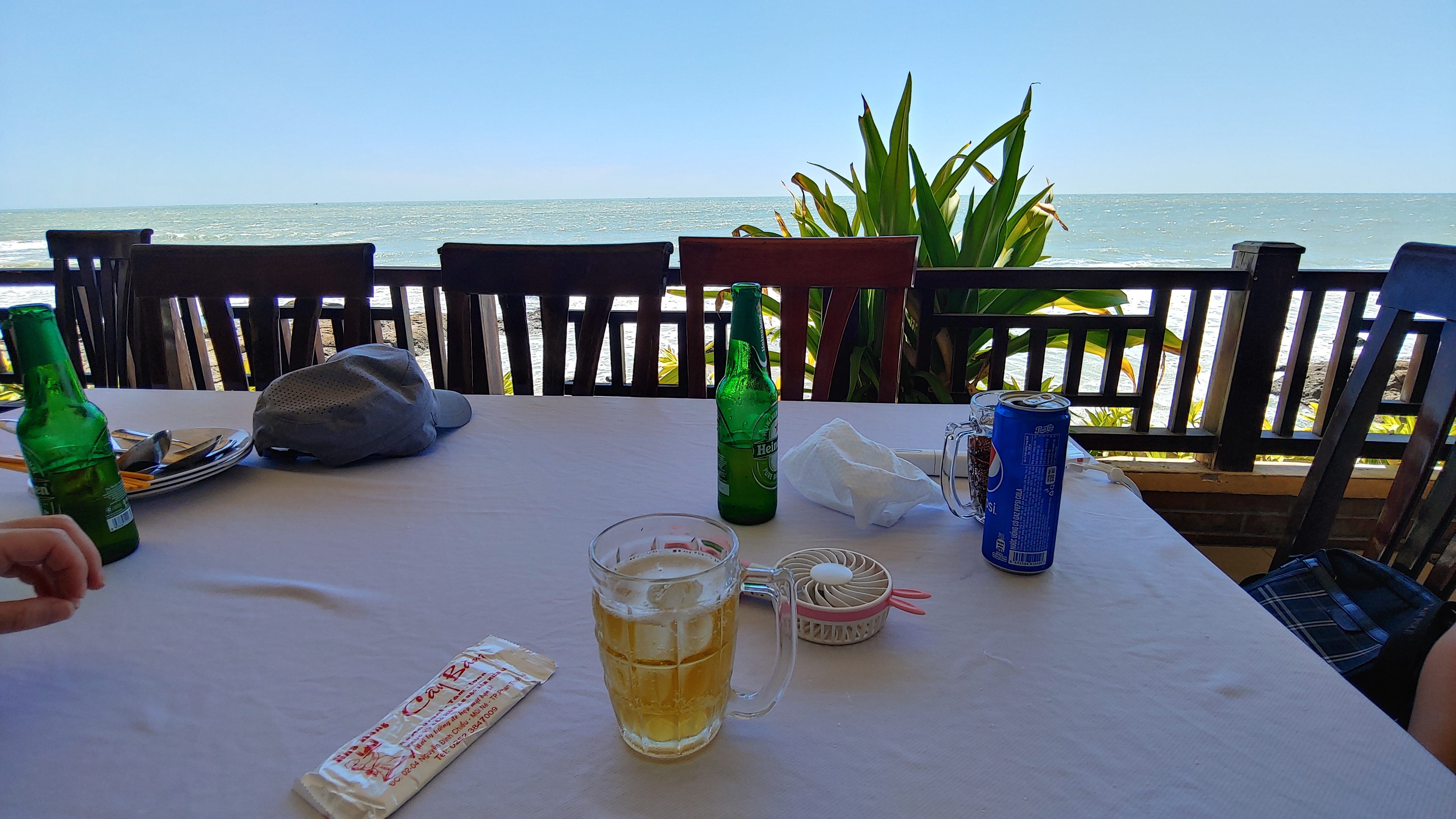 해변 레스토랑 식탁, 맥주잔, 맥주병, 음료 캔, 푸른 바다