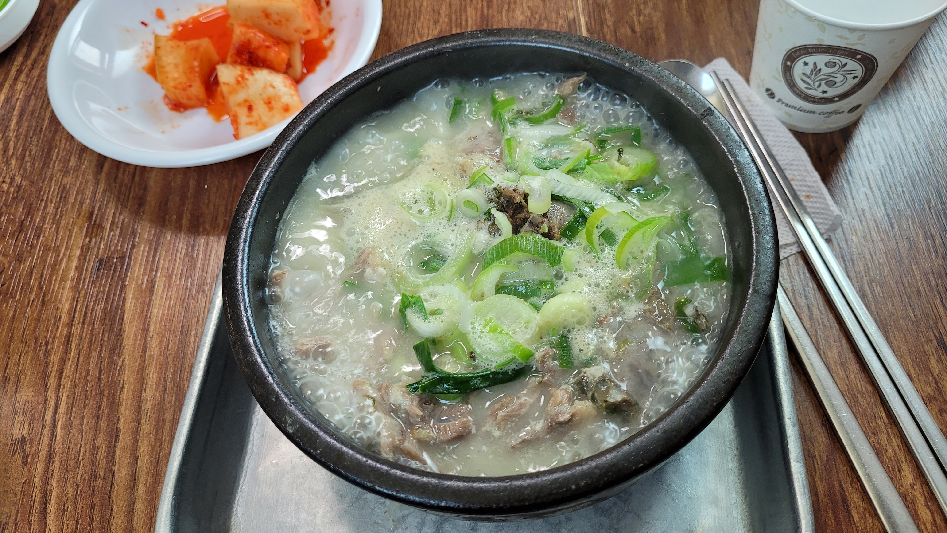 흰 국물 뚝배기 국밥, 송송 썬 대파와 고기, 깍두기.