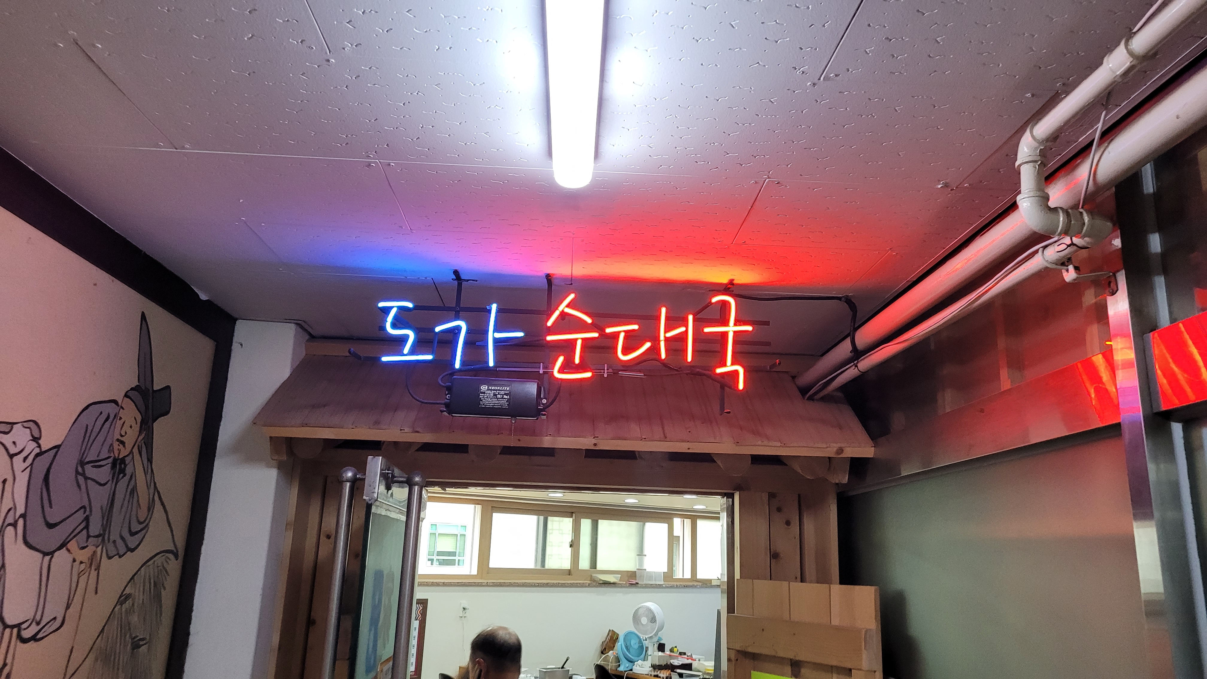 도가 순대국" 네온사인 간판, 푸른색 붉은색 글자, 전통 목재 인테리어.