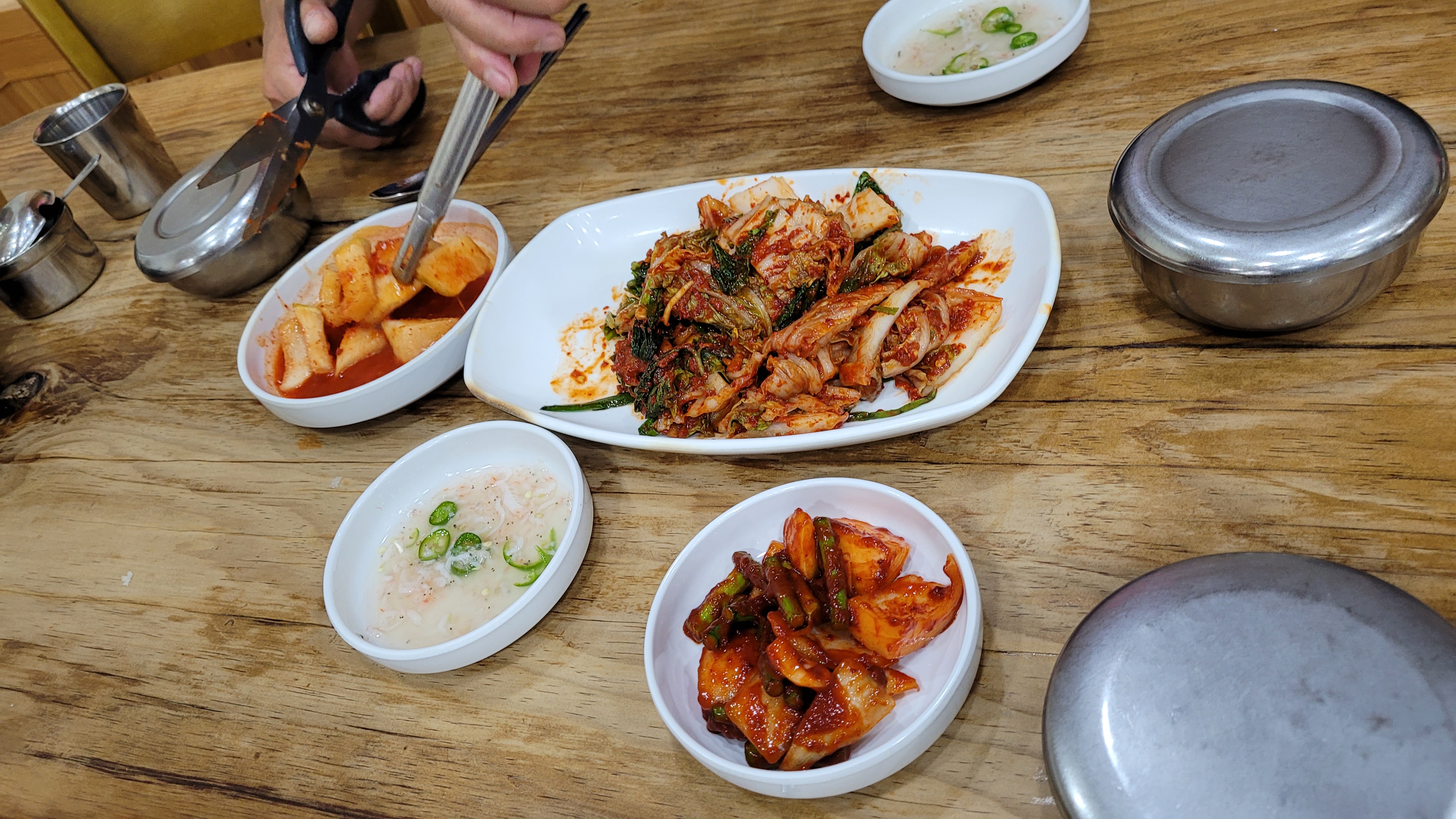 김치, 깍두기, 다양한 한국 반찬, 식사 중 나무 식탁