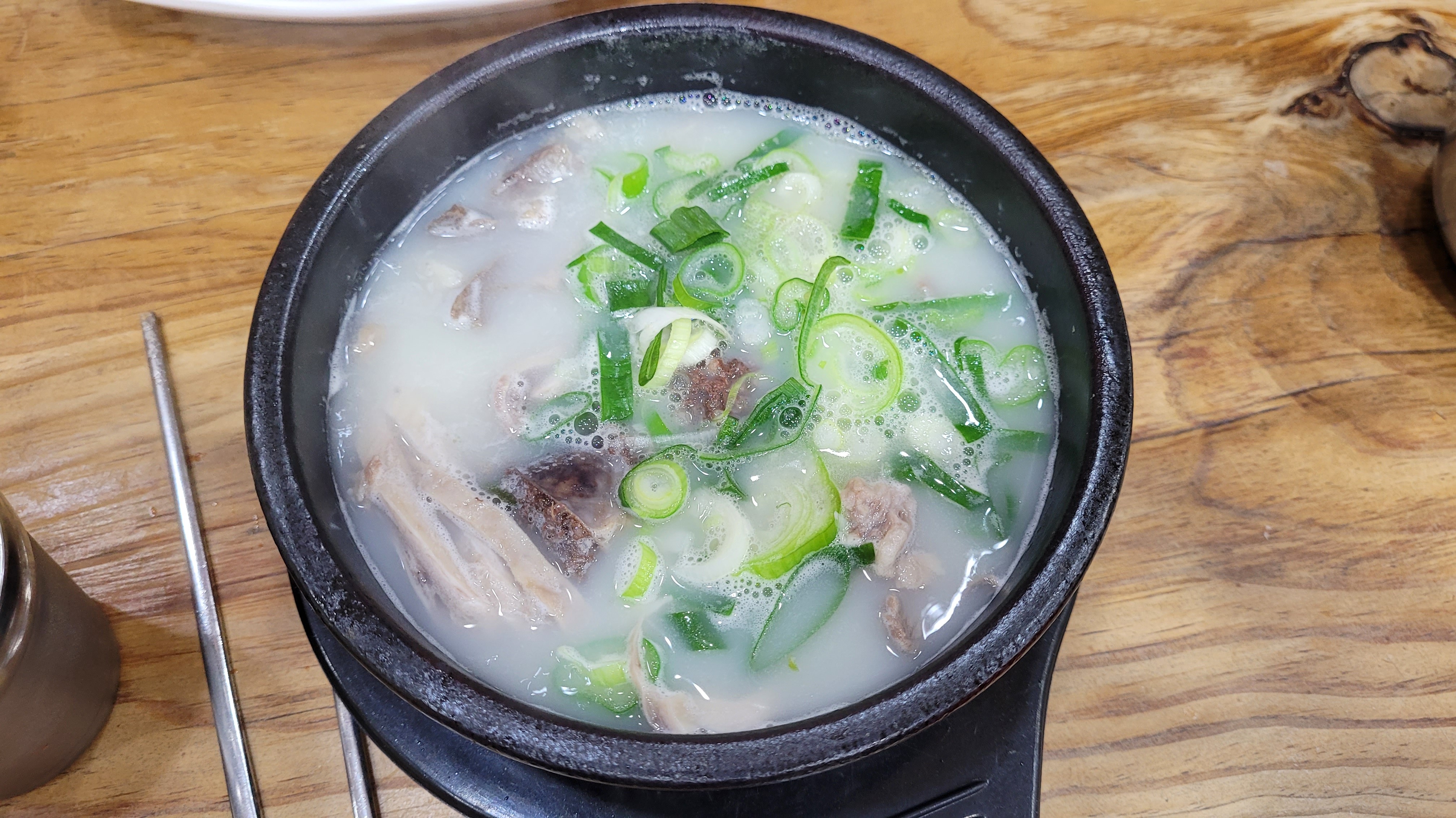 뜨거운 뚝배기 국밥, 뽀얀 국물, 파, 고기 건더기.