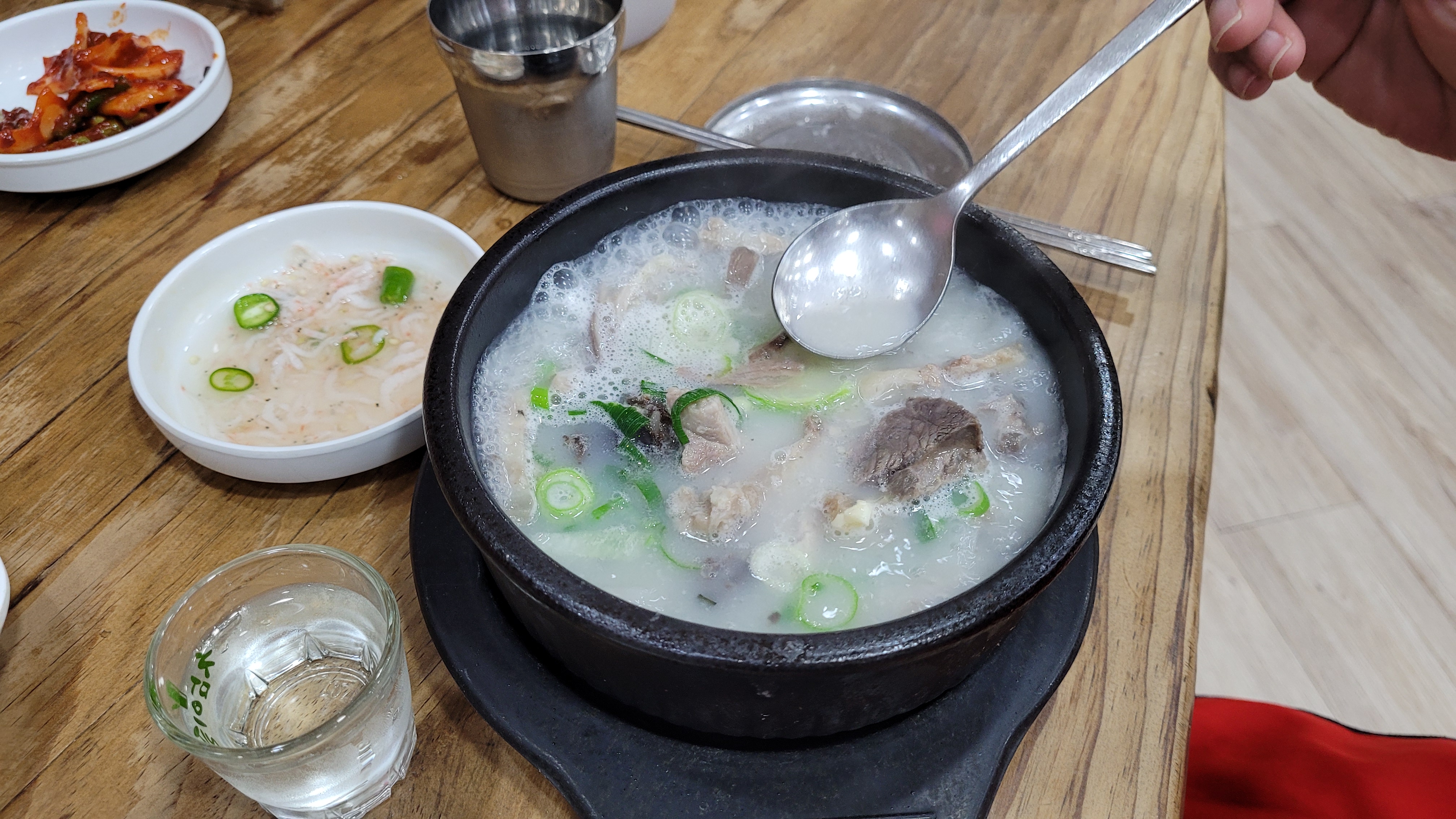 설렁탕, 숟가락, 밑반찬, 소주잔, 나무 식탁 위 식사
