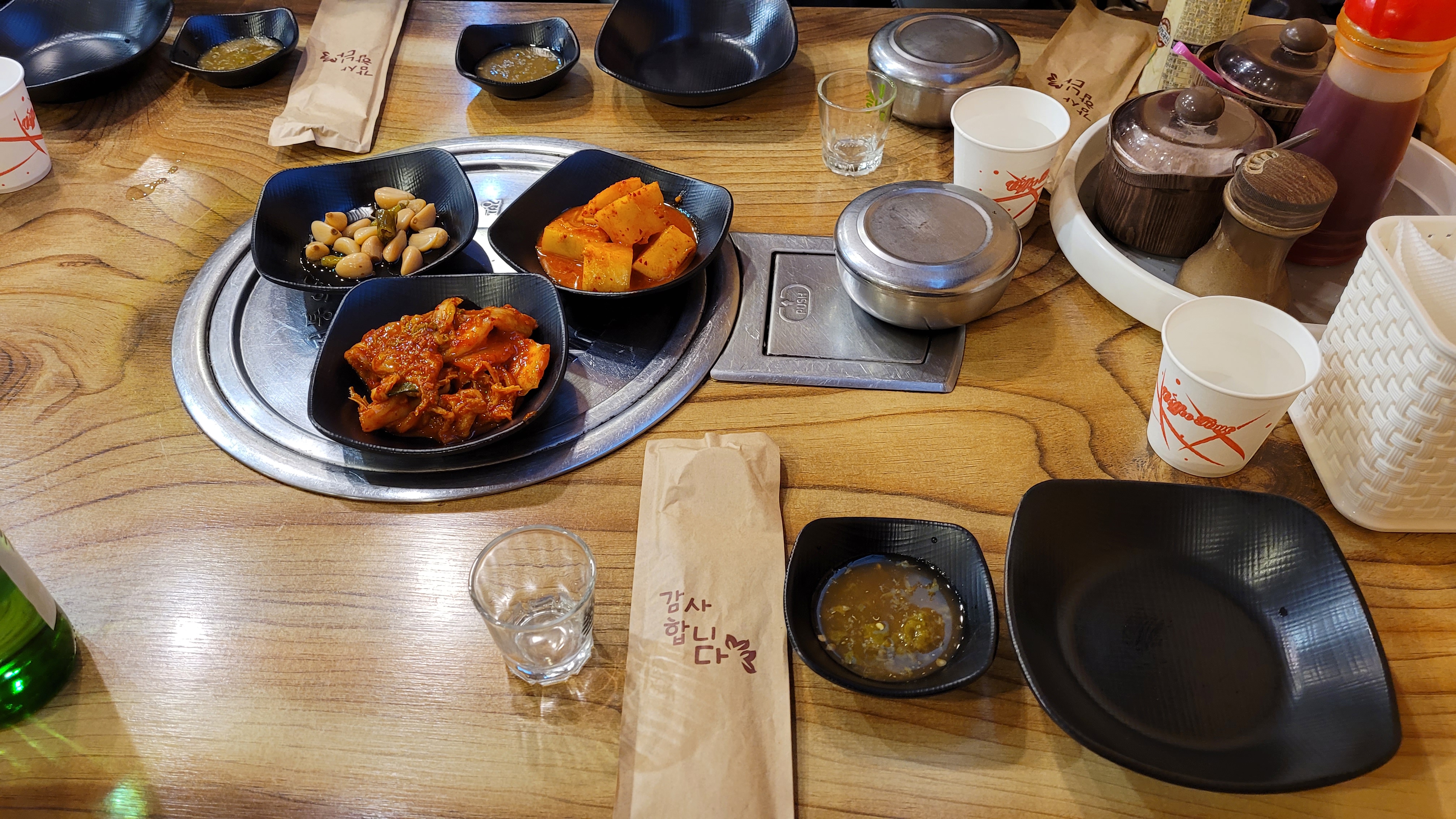 나무 식탁 위 한국 반찬, 김치, 깍두기, 마늘, 술병