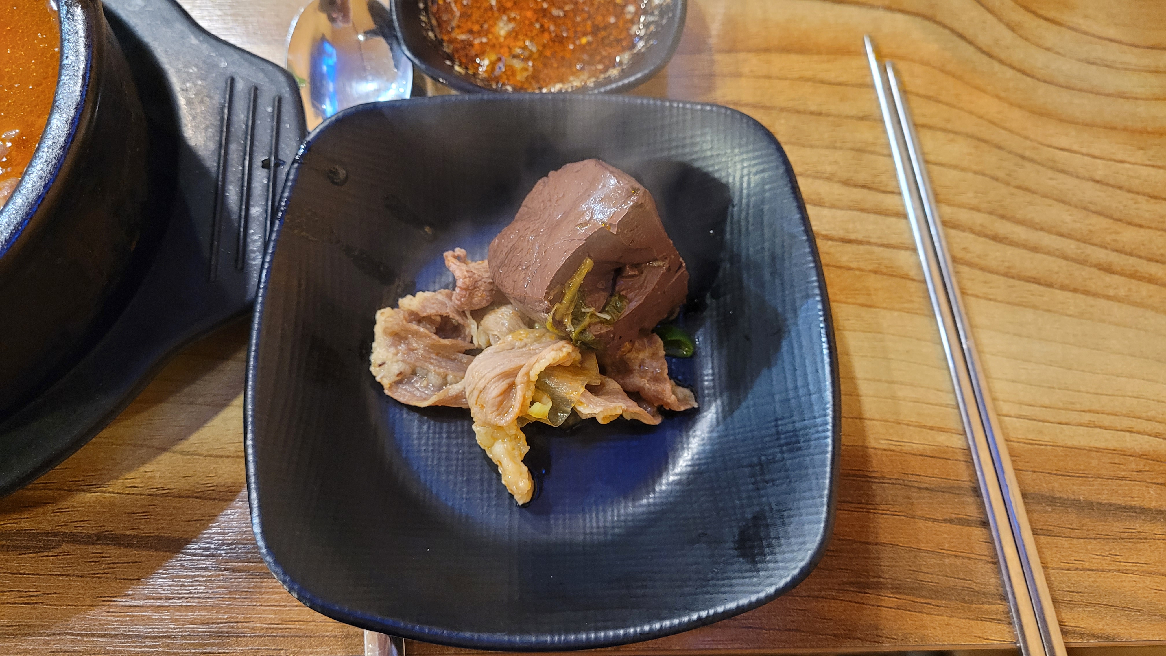 검은 접시에 담긴 선지, 부드러운 내장 고기, 채소