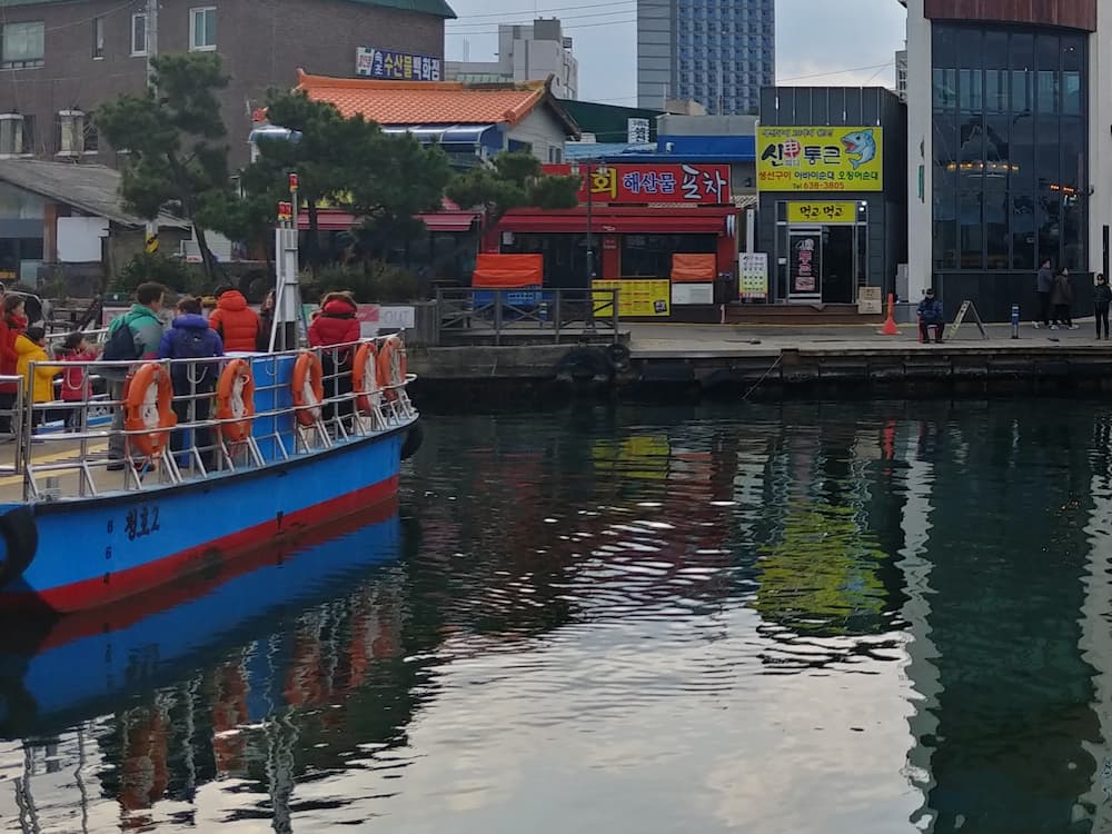 파란색 빨간색 유람선, 구명조끼, 항구, 해안가 건물 반사