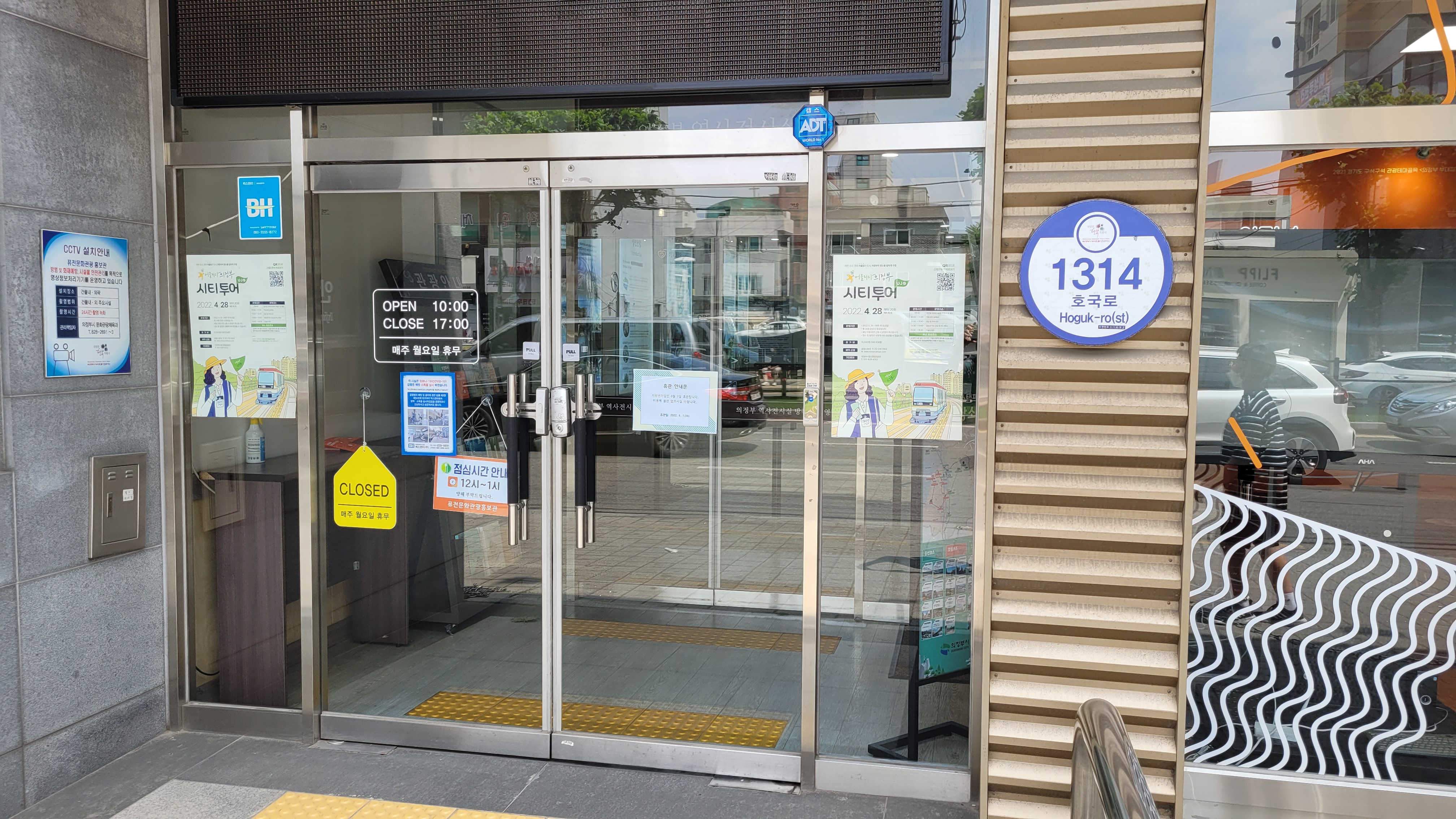 유리문 입구, 영업시간 안내, 시티투어 포스터, 주소 1314 호국로, 주변 반사