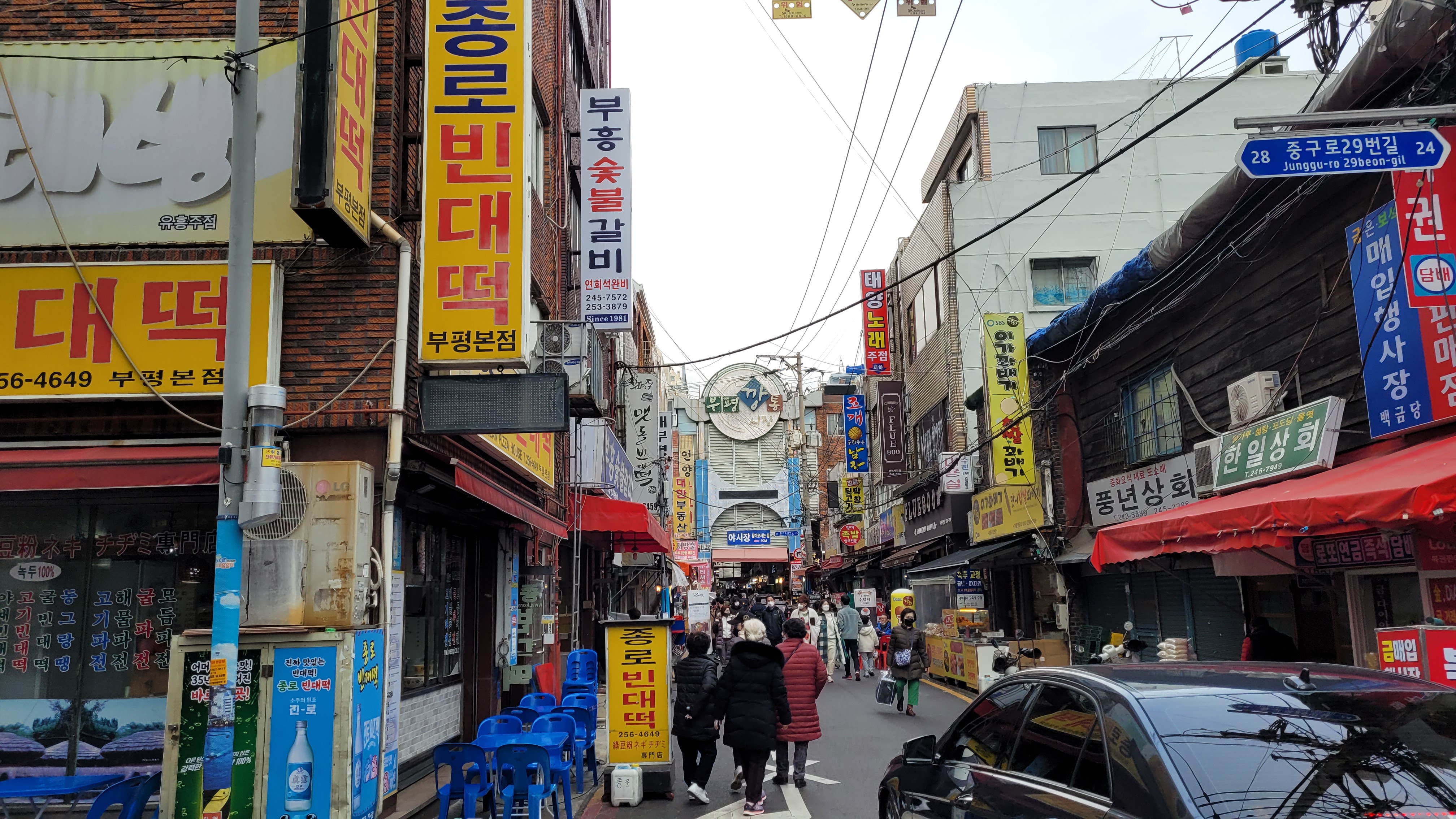 한국 번화가 시장 골목, 상점 간판과 북적이는 보행자
