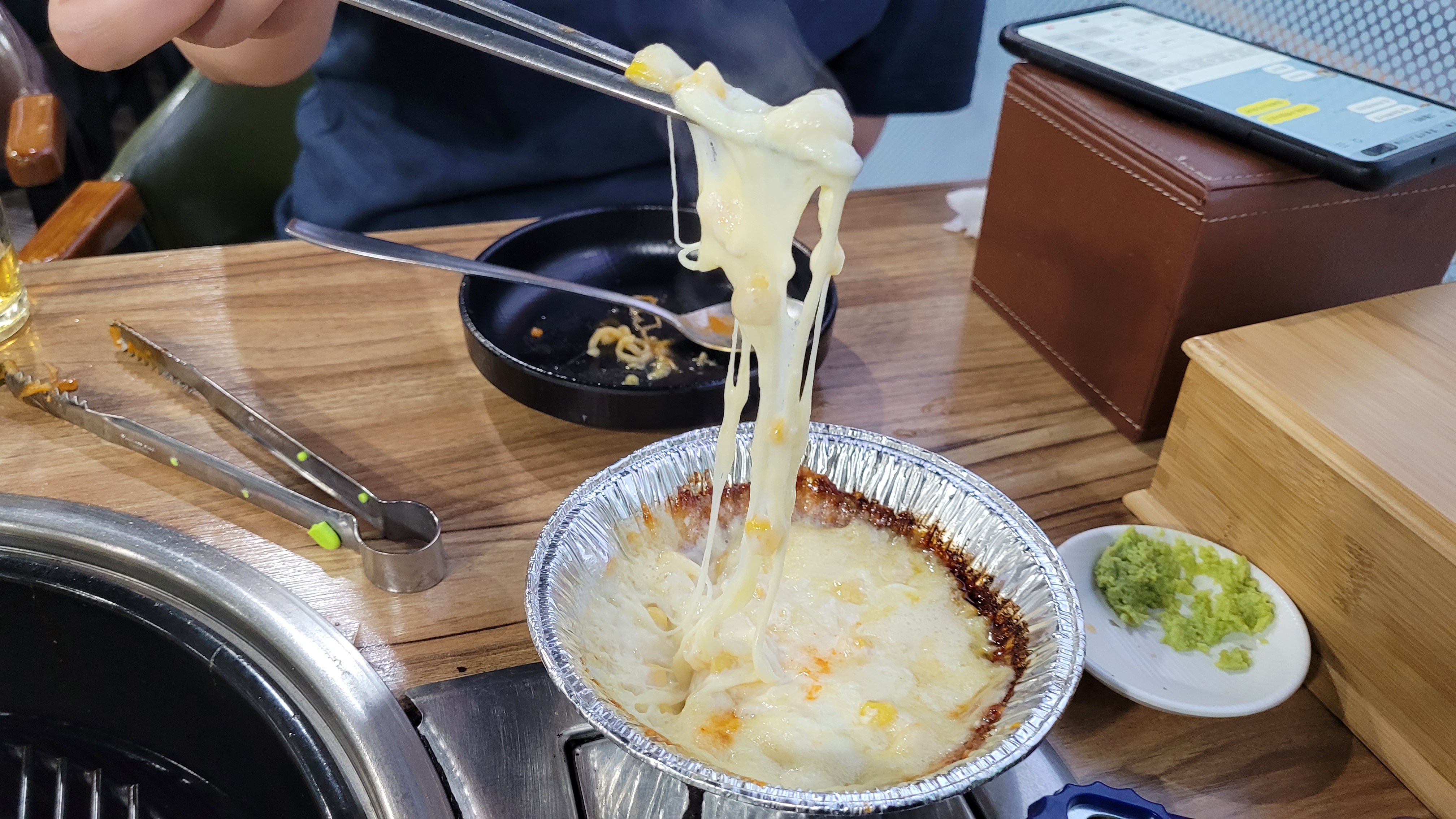 젓가락으로 길게 늘어나는 녹은 치즈 콘치즈, 식당 테이블