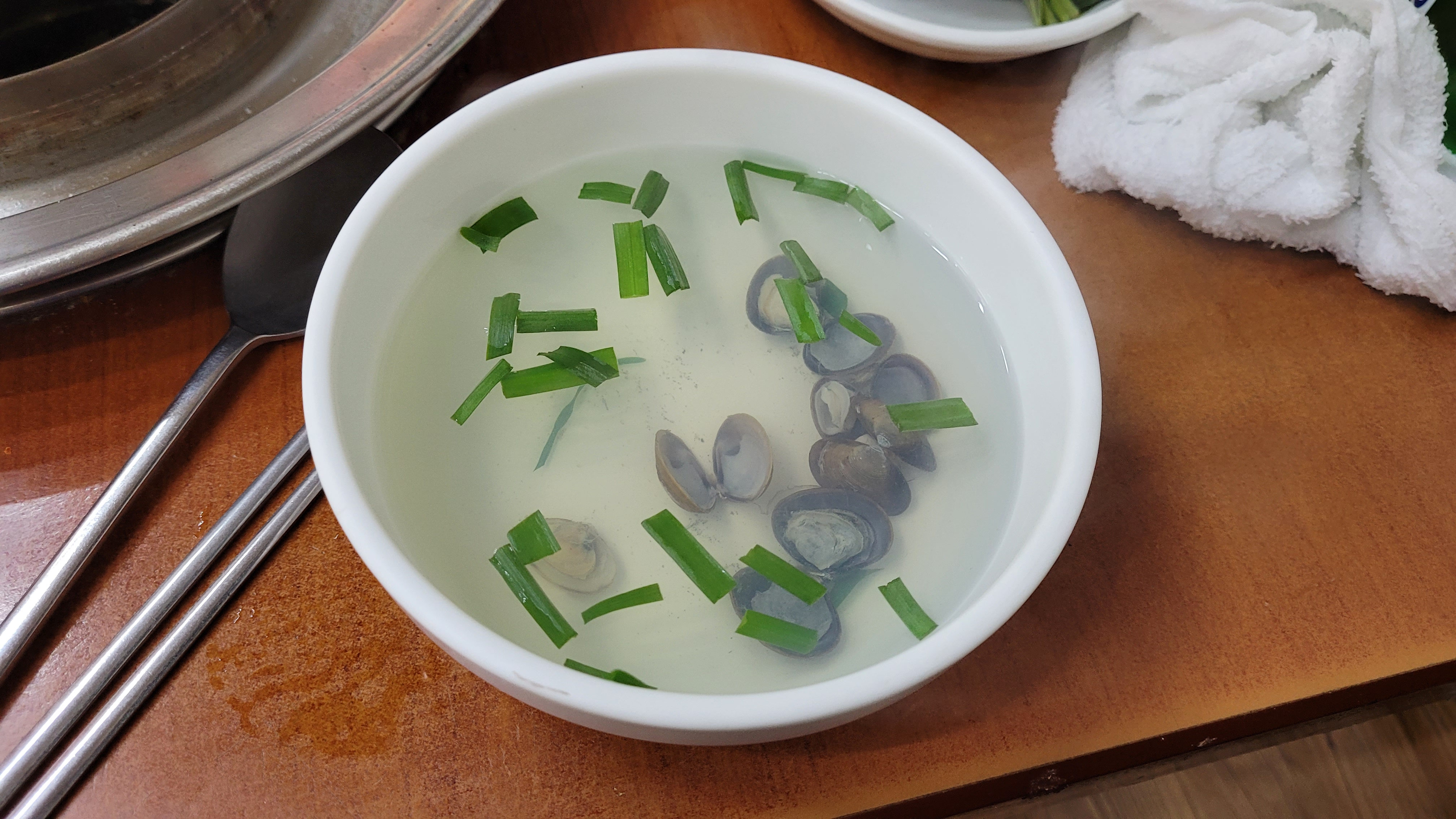 작은 조개, 맑은 국물, 송송 썬 파, 하얀 그릇, 나무 탁자