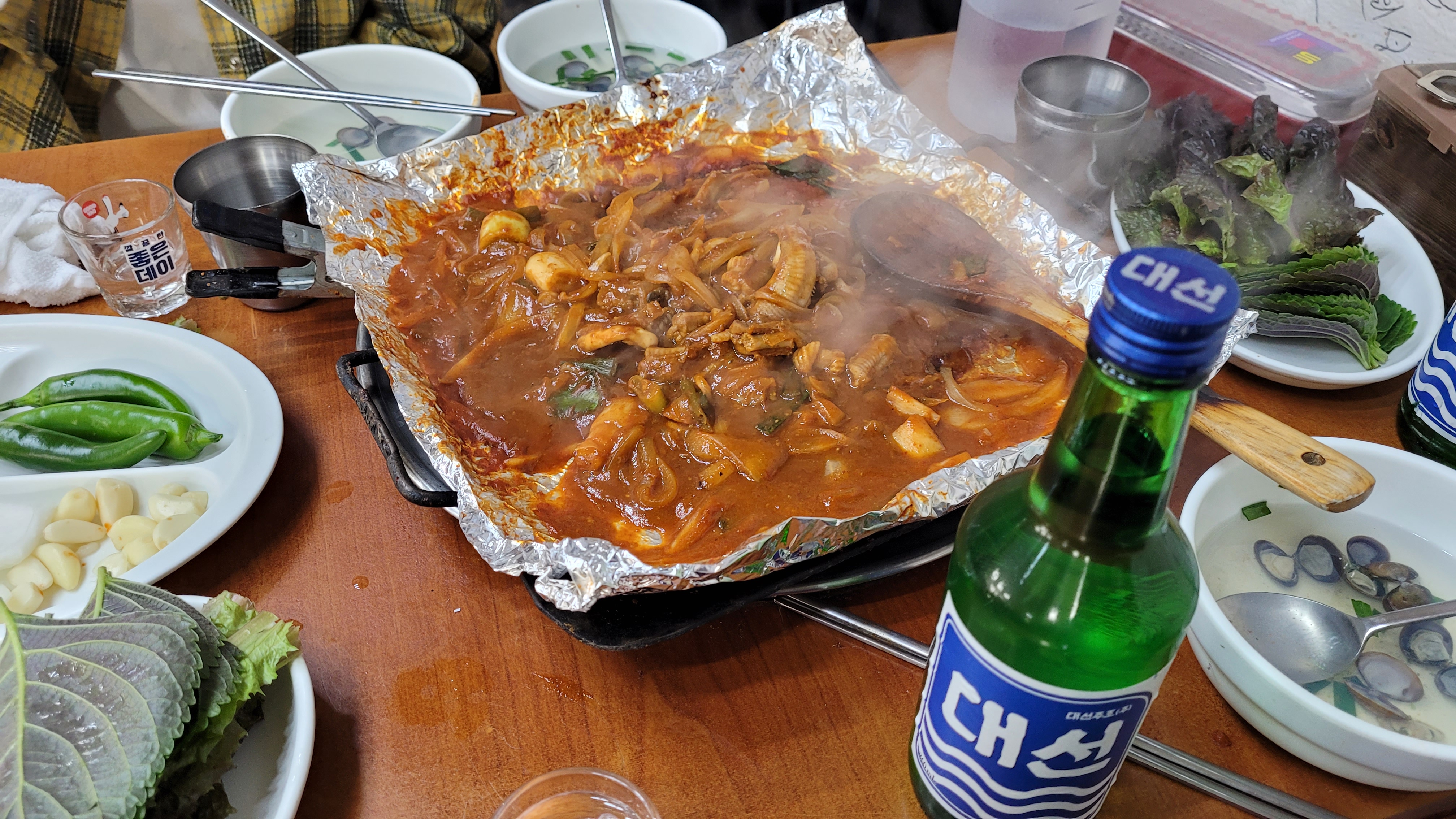 김이 나는 은박지 매콤 볶음요리, 대선 소주, 쌈 채소, 조개탕