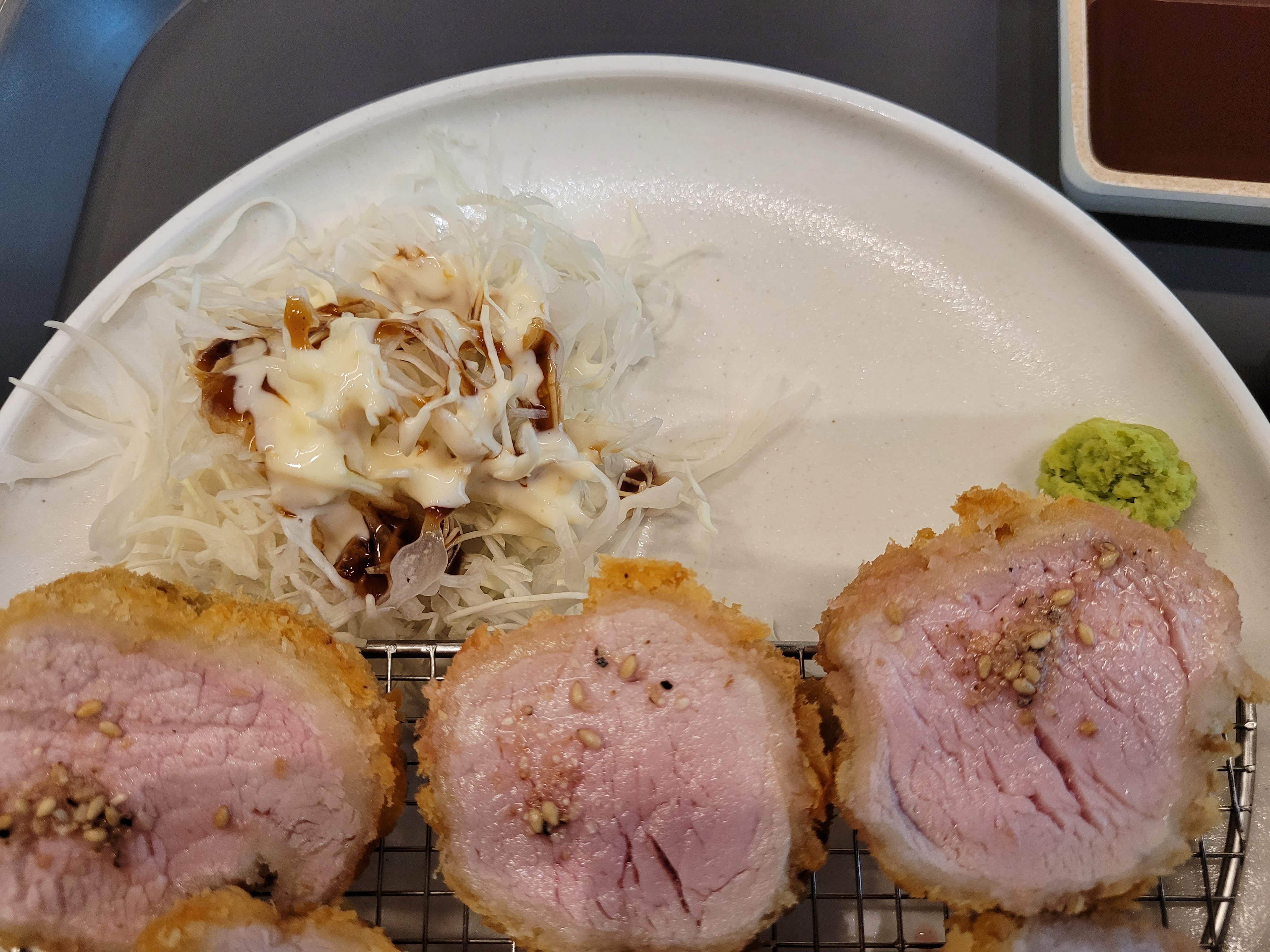 바삭한 돈카츠, 깨 뿌려진 분홍 돼지고기, 양배추 샐러드, 소스, 와사비.
