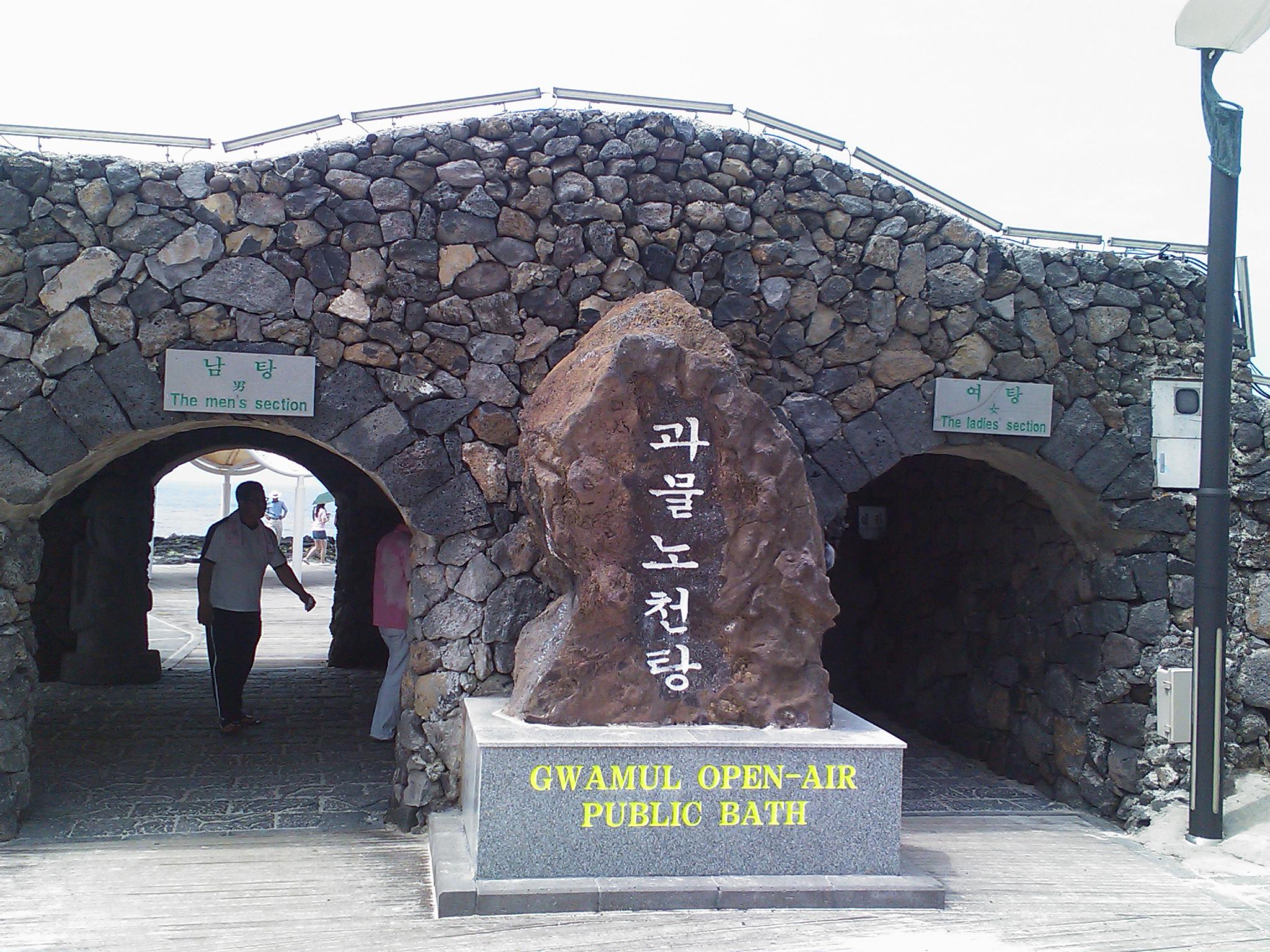 과물 노천탕 화산암 아치형 입구, 중앙에 큰 안내석.