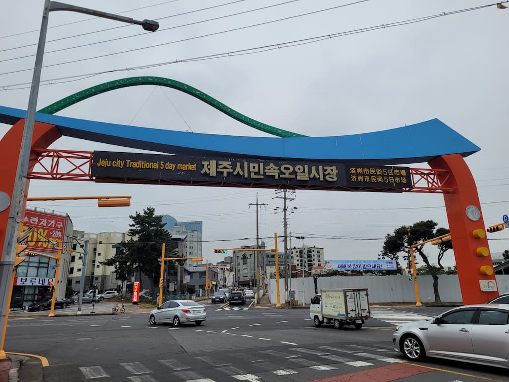 제주시 민속오일시장 아치, 주황색 파란색, 거리 차량, 건물