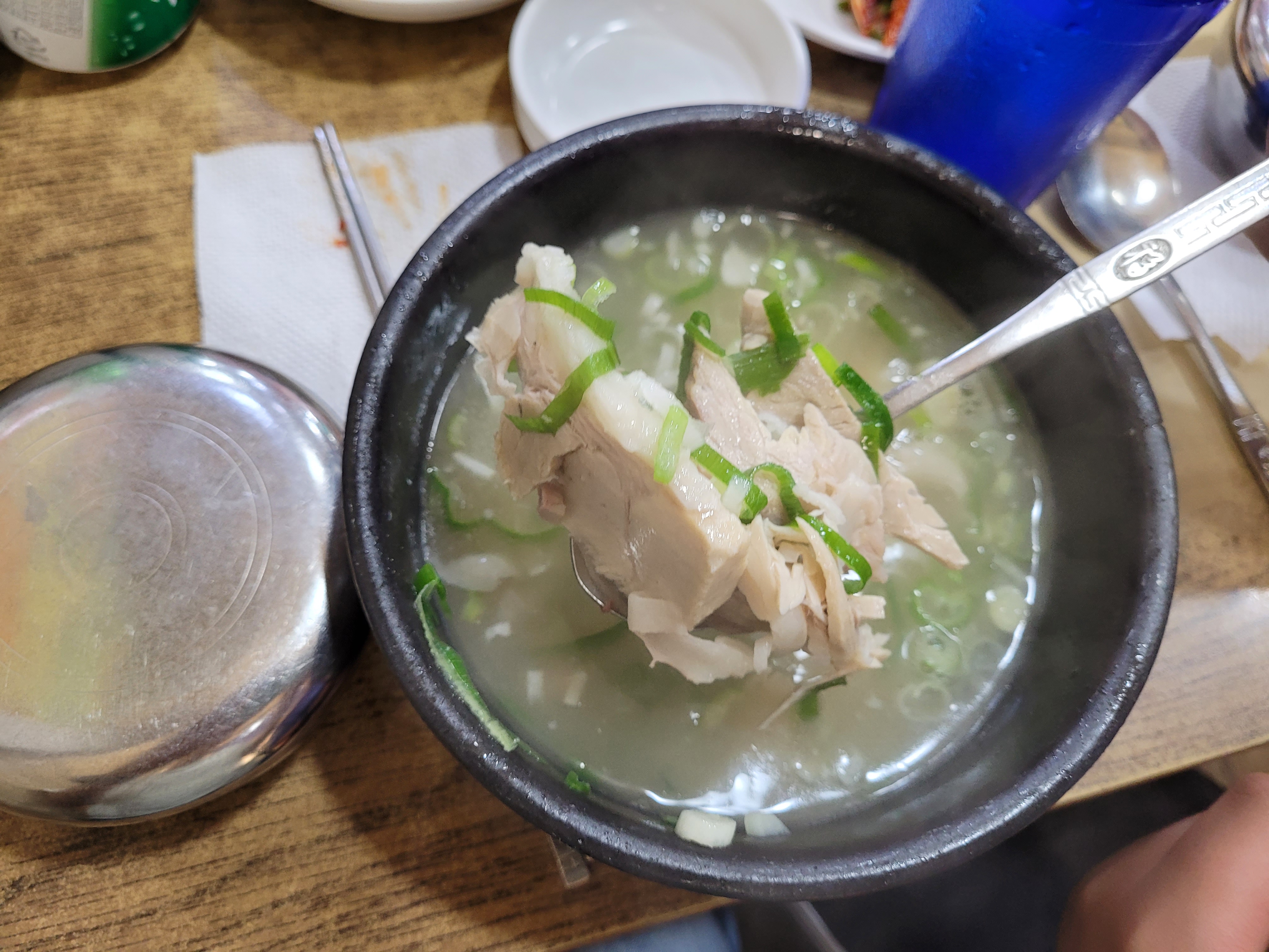 따뜻한 고기 국밥, 파 고명, 숟가락으로 떠올린 고기