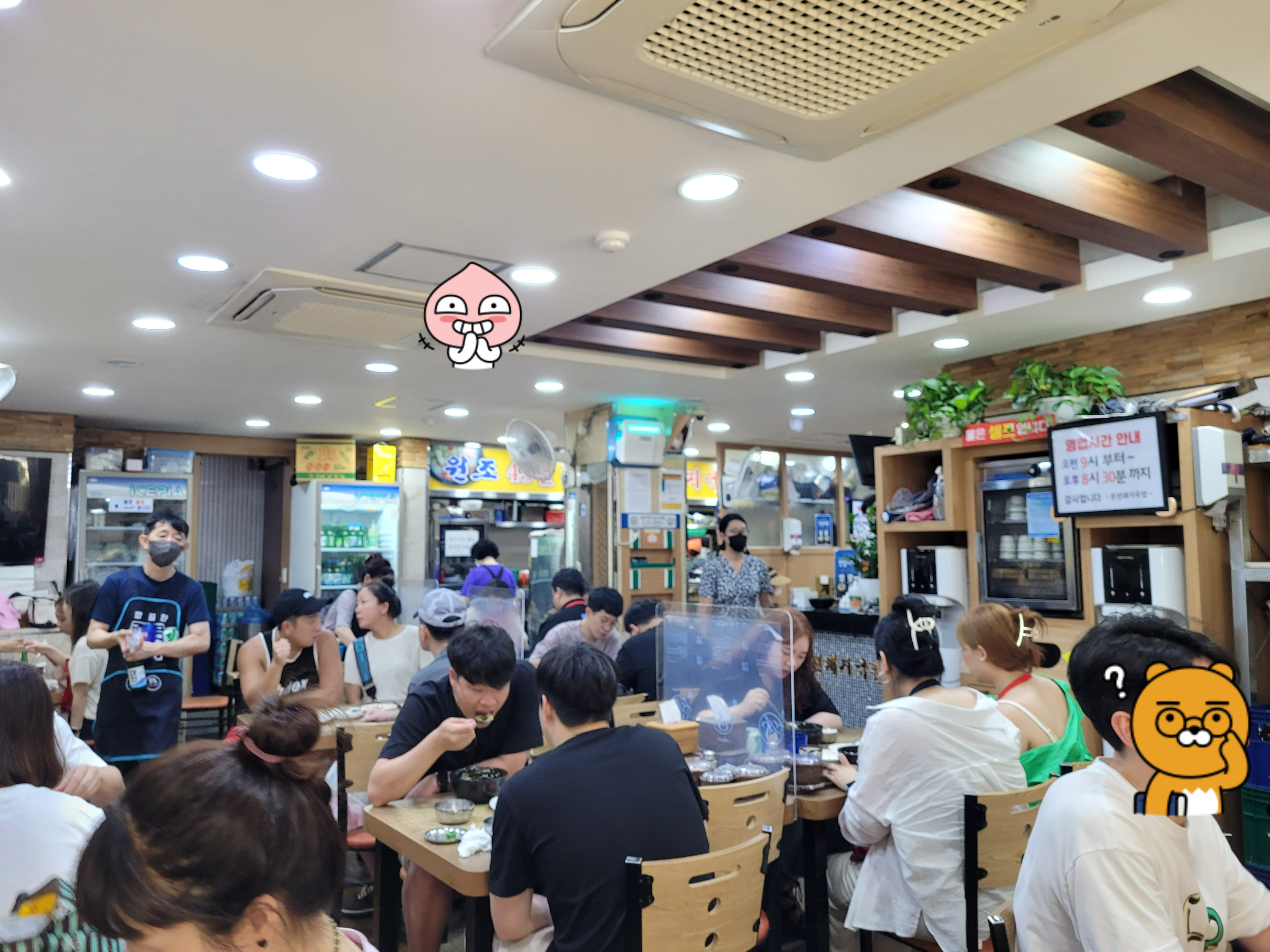 북적이는 식당 내부, 손님들 식사, 나무 테이블, 밝은 조명