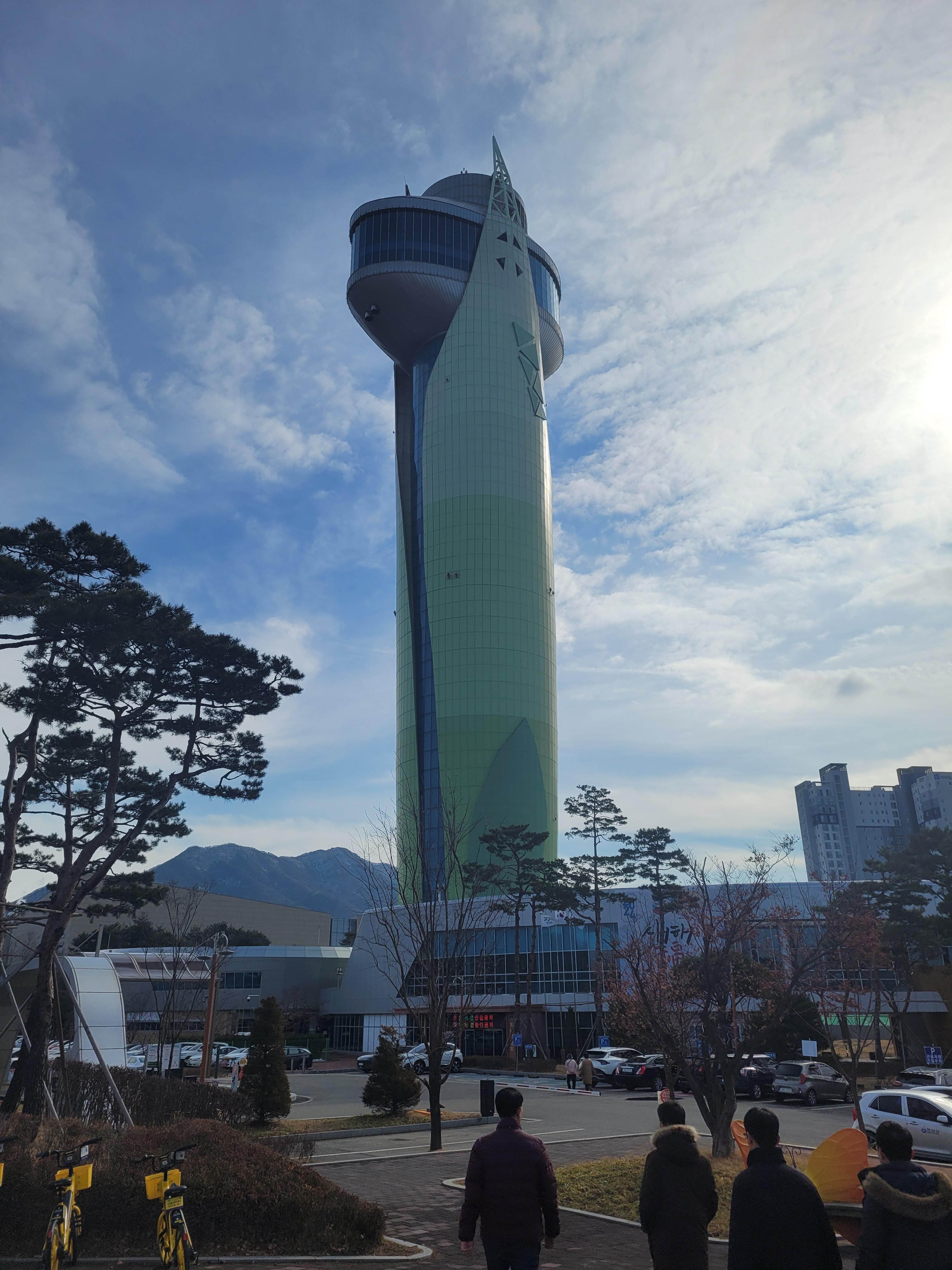 푸른 하늘 구름 아래, 녹색 현대식 전망 타워, 소나무, 산.