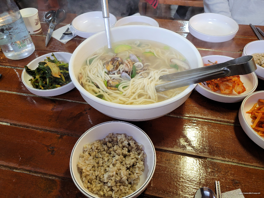 뜨거운 바지락 칼국수, 김치, 보리밥, 나무 식탁