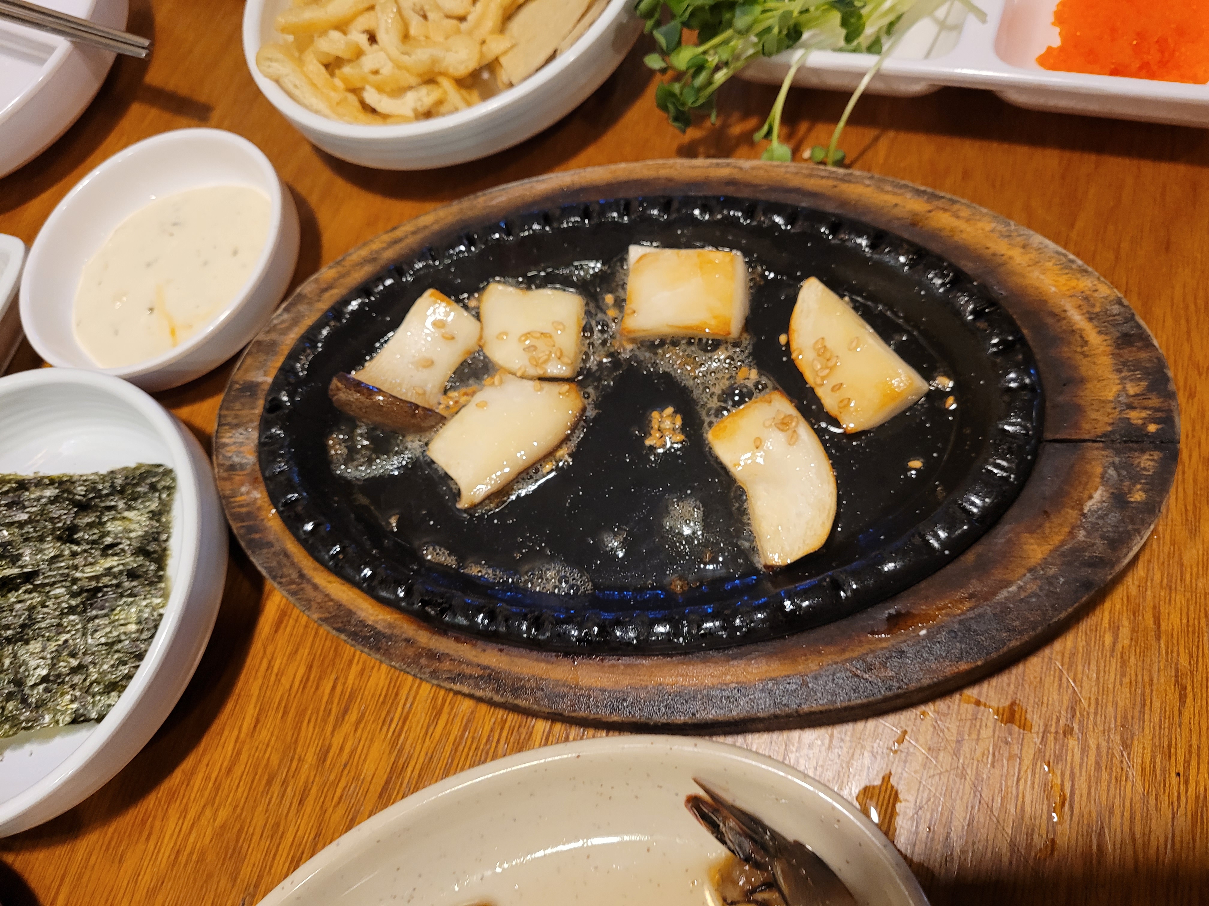 뜨거운 철판 위 지글거리는 새송이 버섯 구이와 여러 반찬