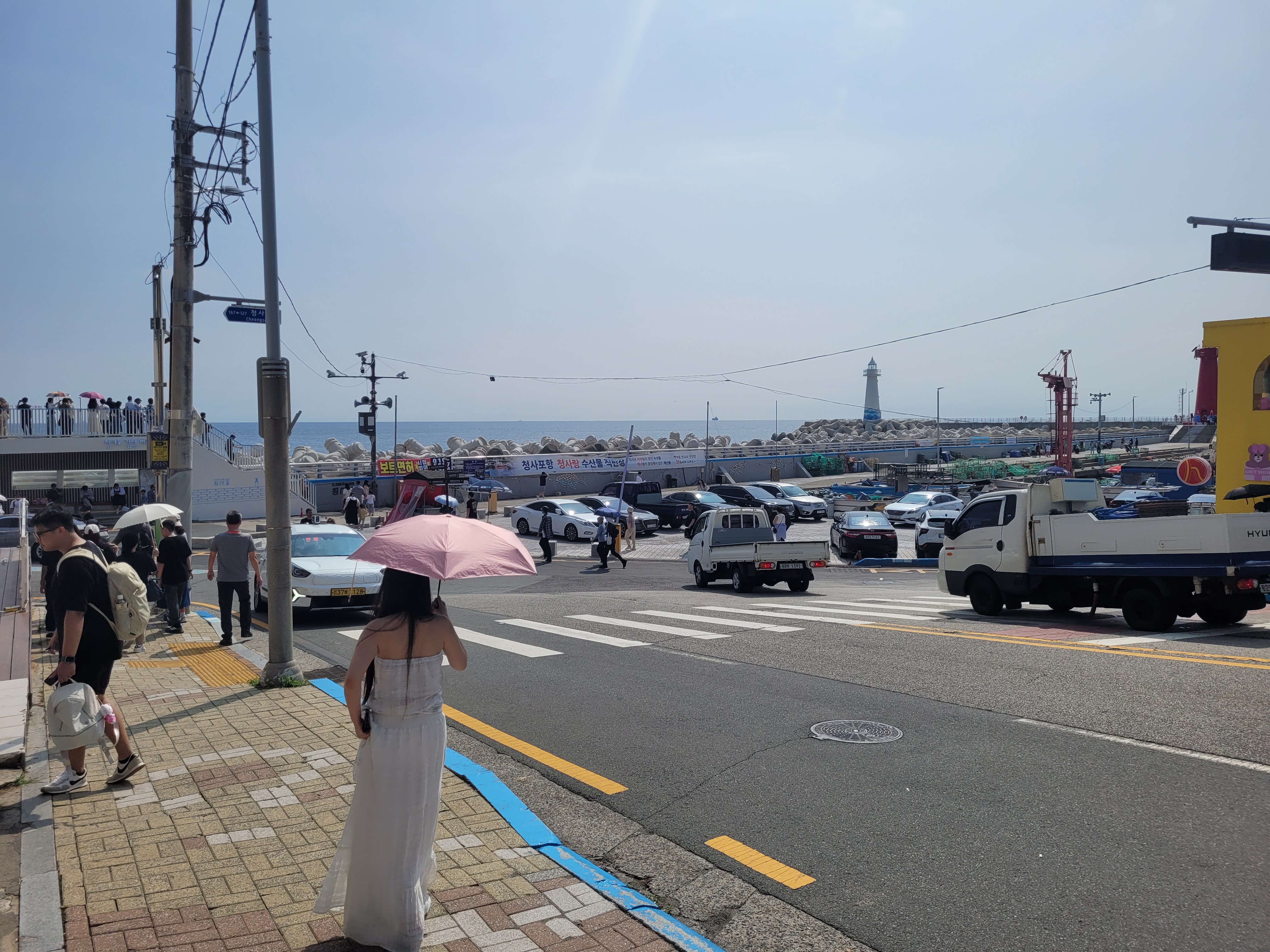 맑은 날 해안 도로, 등대 항구, 차량, 보행자.