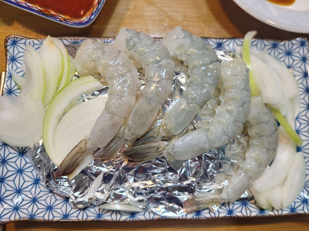 푸른 문양 접시 위 신선한 껍질 벗긴 생새우, 흰 양파