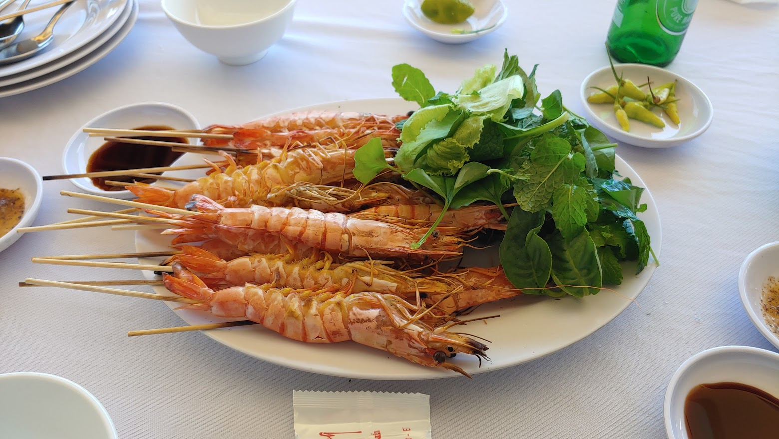 노릇한 새우 꼬치 구이, 신선한 민트, 다양한 소스, 흰 식탁