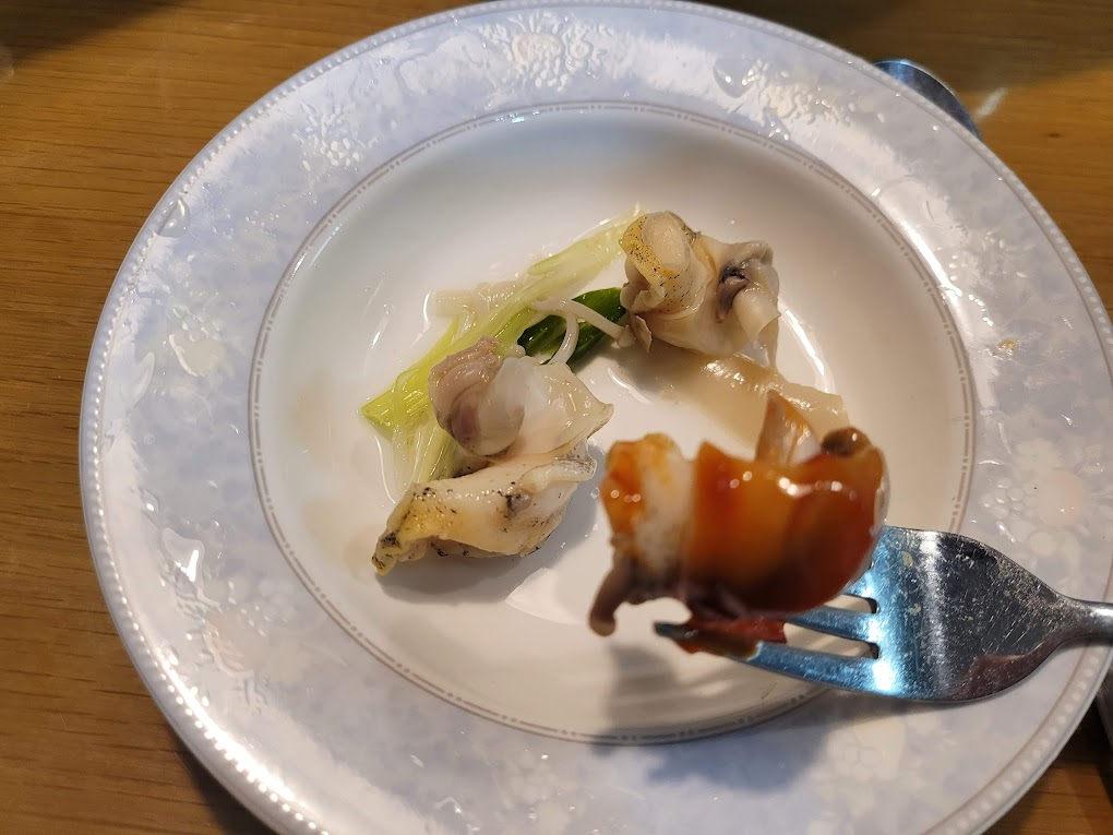 하얀 접시 위 해산물, 포크에 찍힌 양념 전복